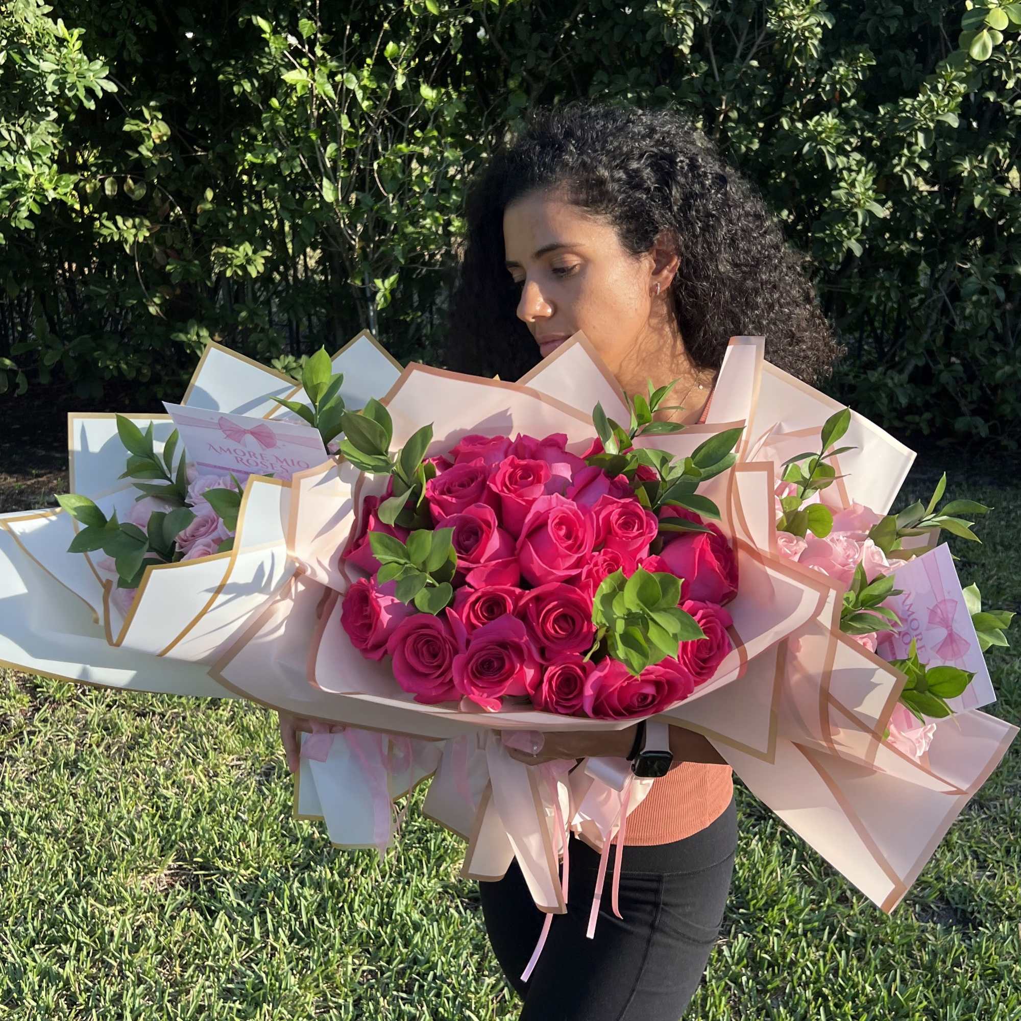 Woman holding several large bouquets of hot pink roses