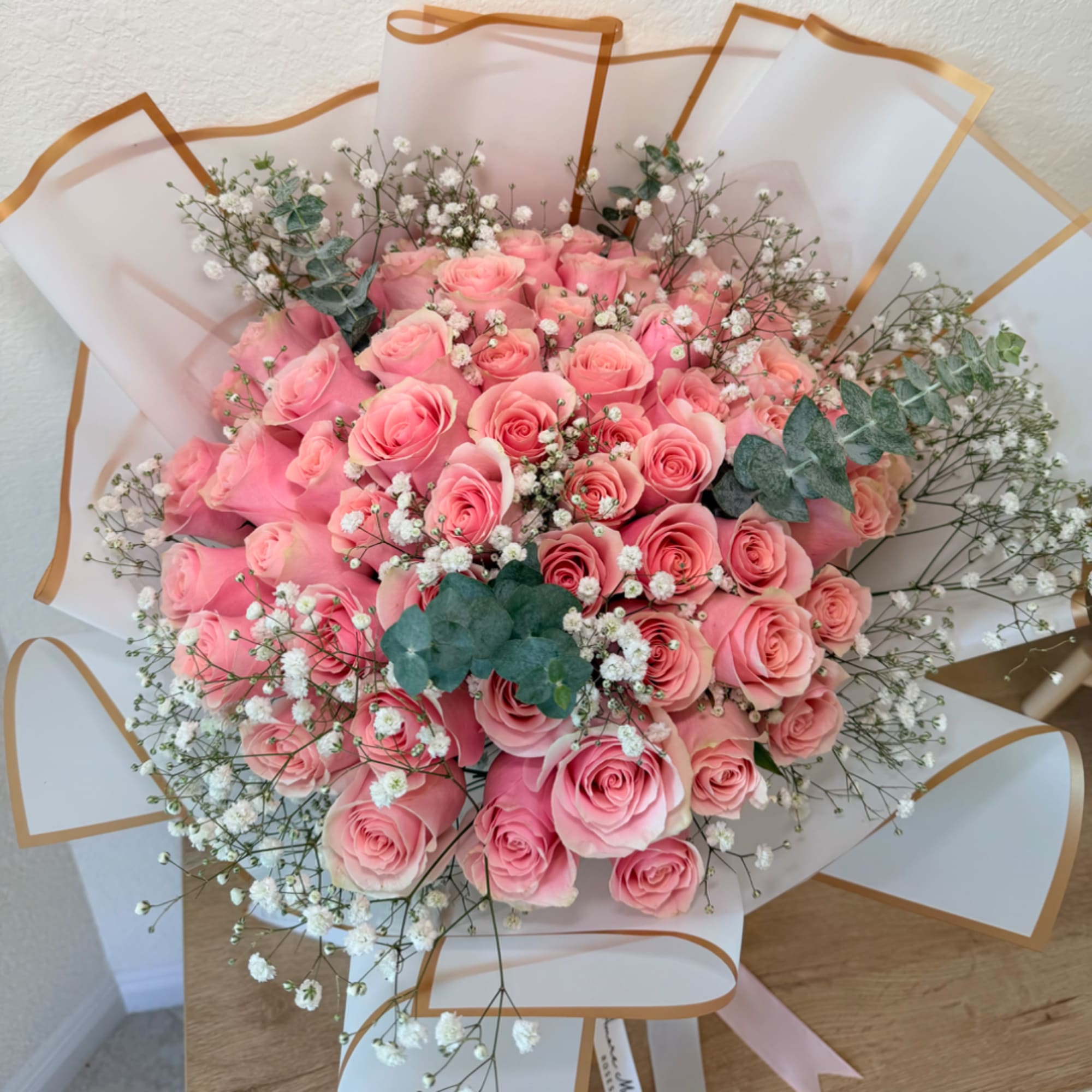 Bouquet of pink roses with baby's breath and eucalyptus in white wrap