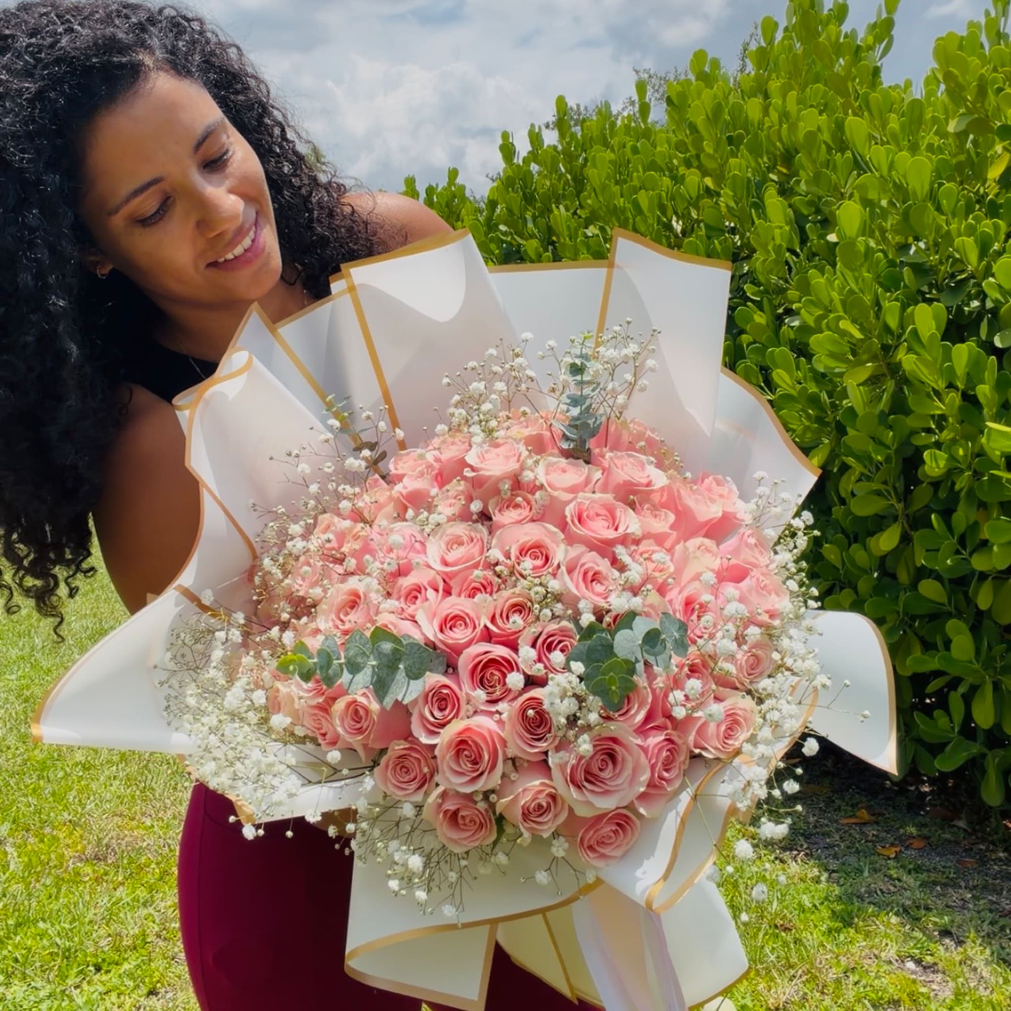 Woman holding a large bouquet of pink roses wrapped in white paper
