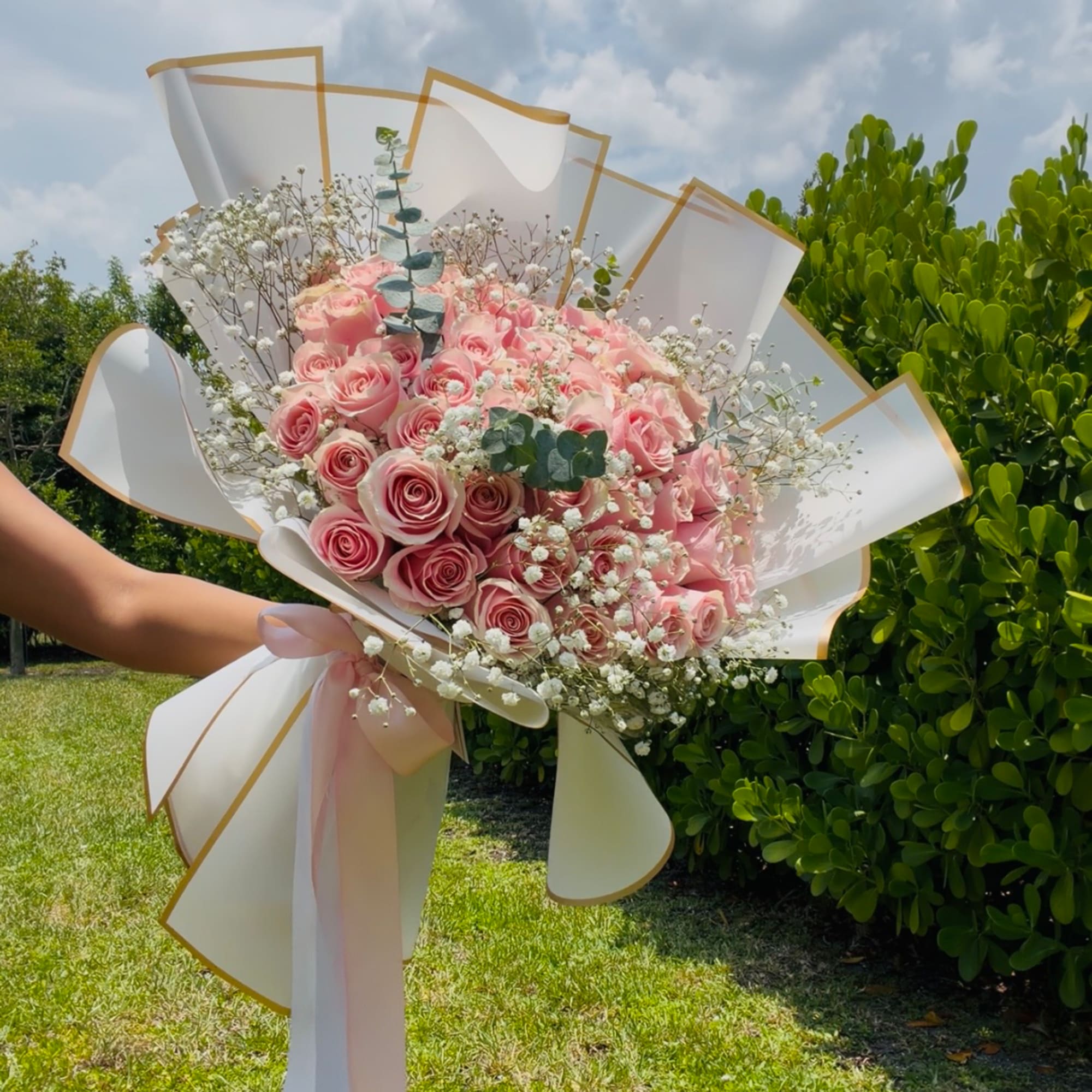 Large bouquet of pink roses wrapped in white paper with a pink ribbon
