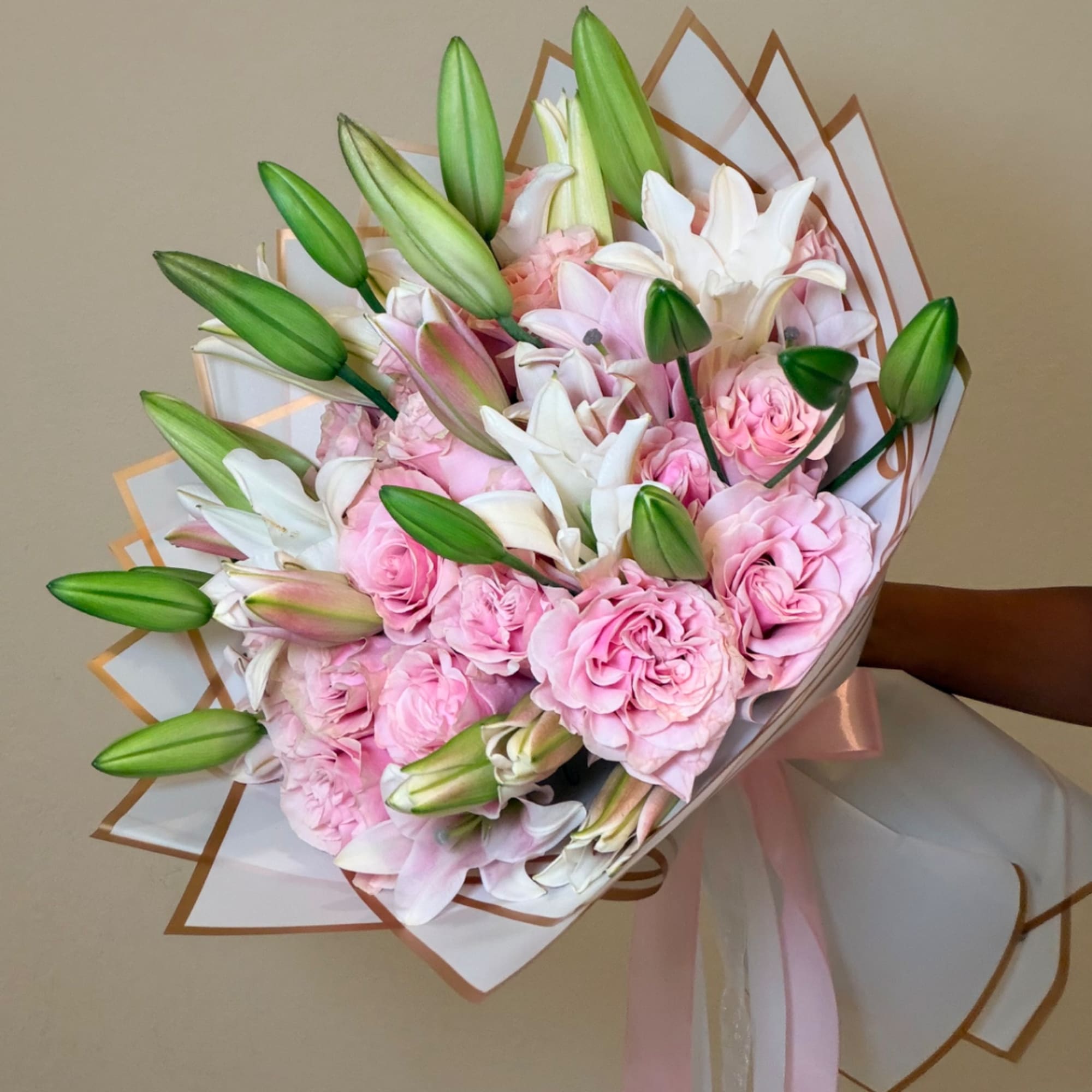 Bouquet of pink roses and white lilies wrapped in white paper