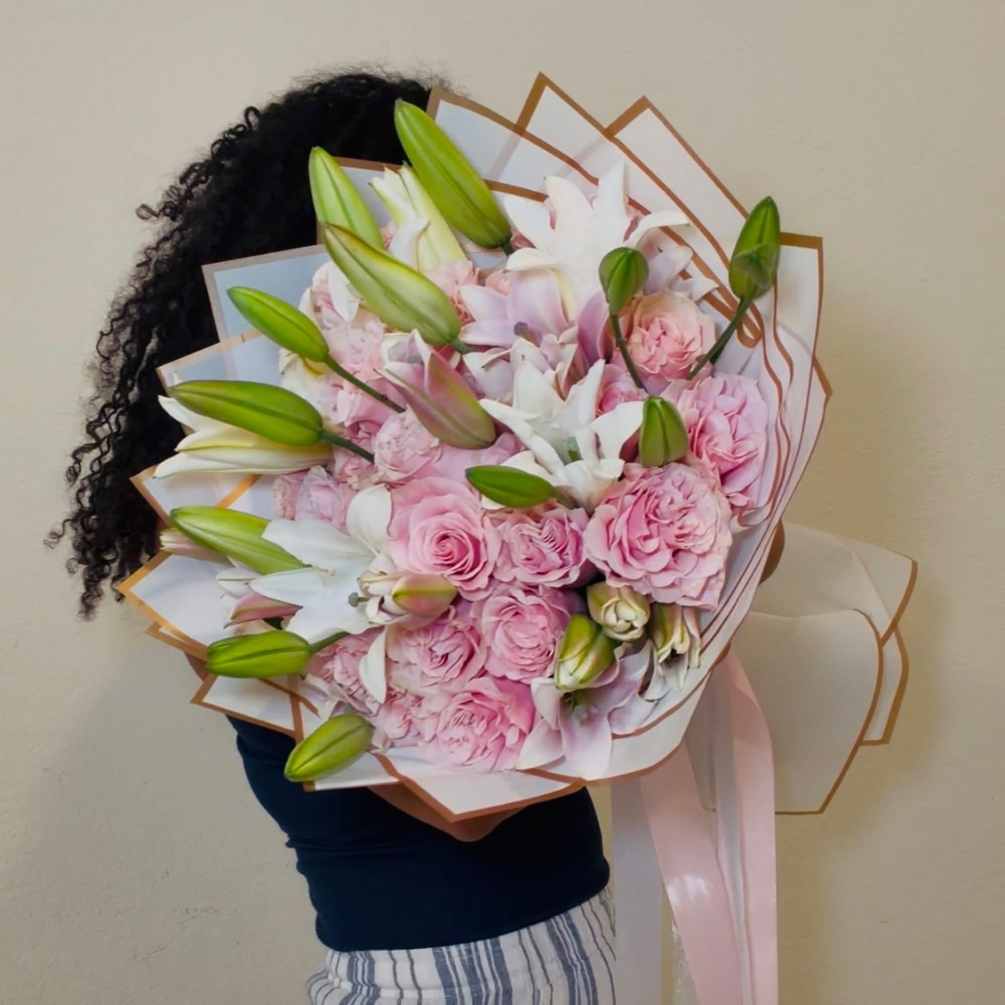 Large bouquet of pink roses and white lilies wrapped in paper
