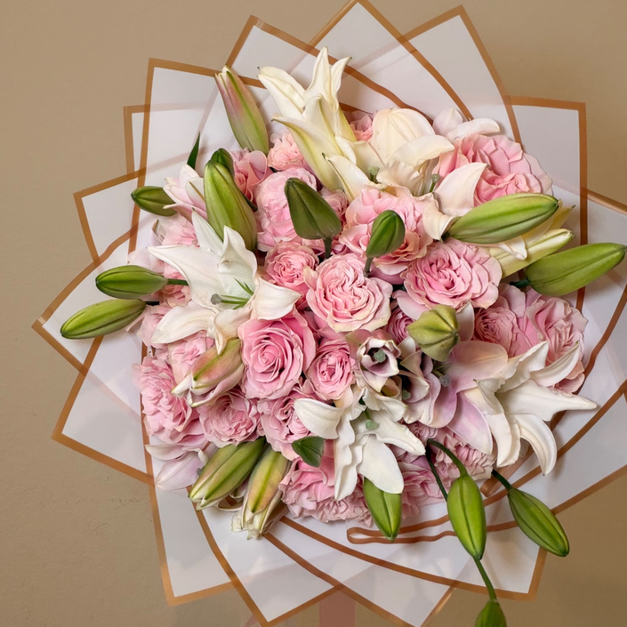Pink roses and white lilies arranged in a wrapped bouquet