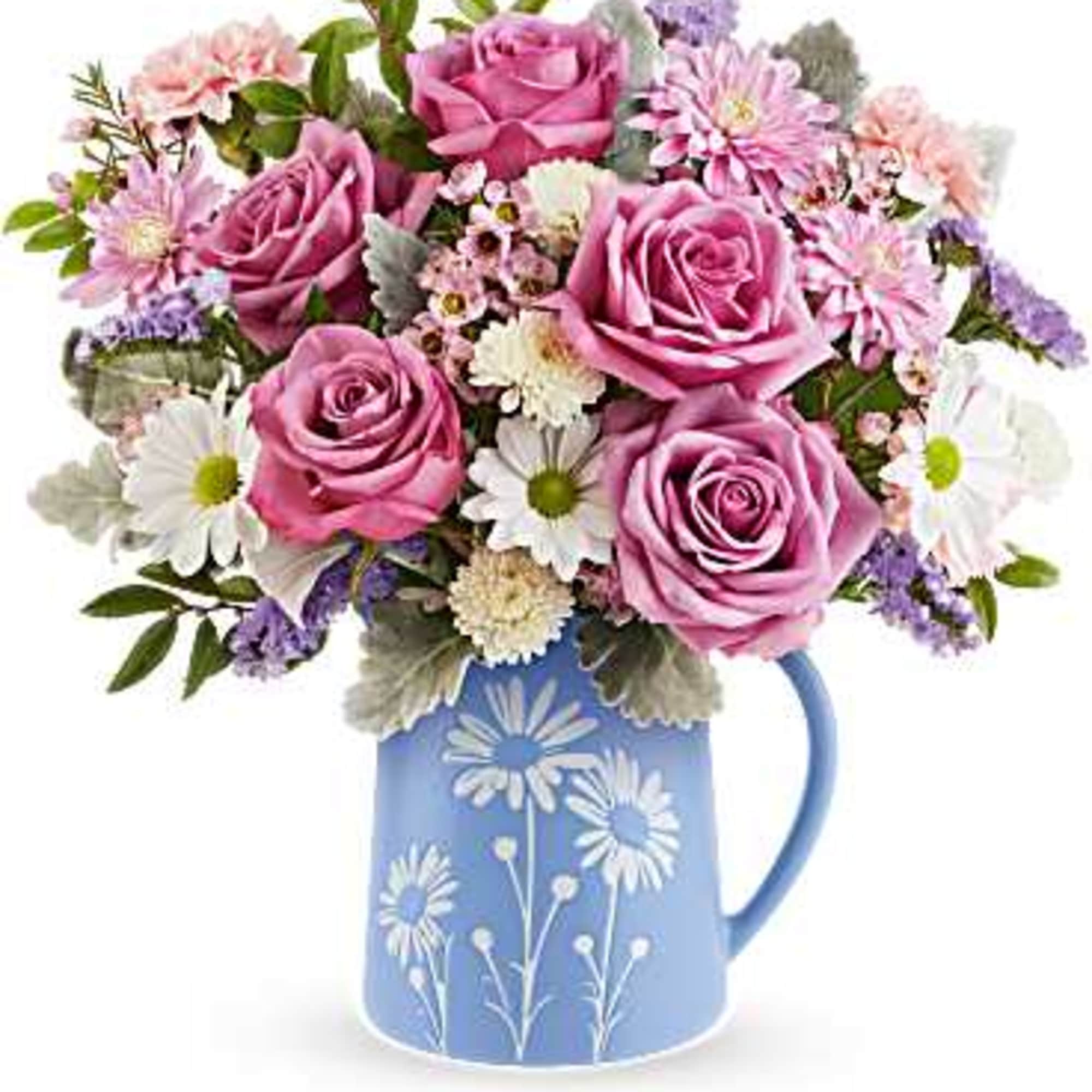 Pink roses and daisies arranged in a blue floral pitcher