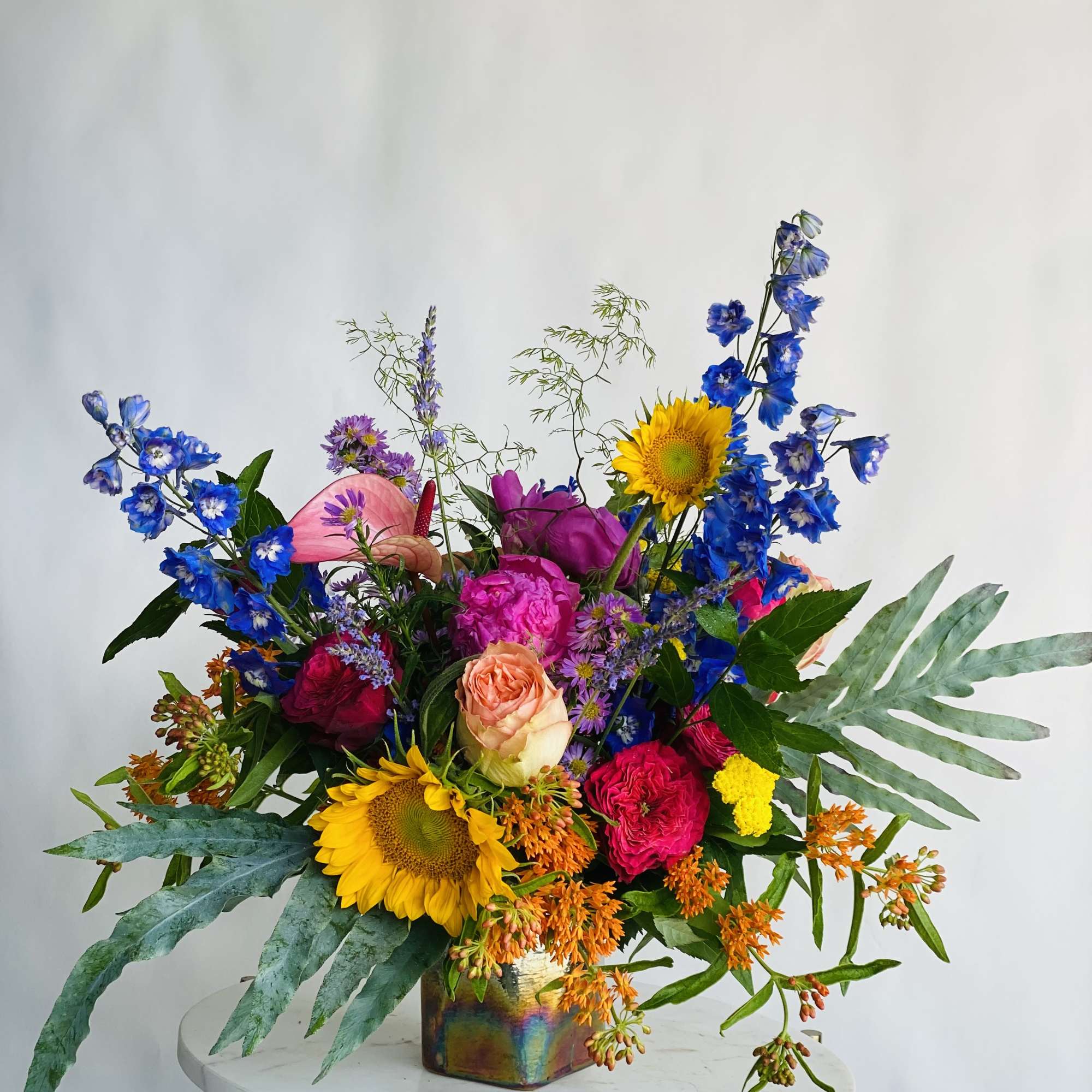 Colorful mixed bouquet in a metallic vase with sunflowers and blue flowers