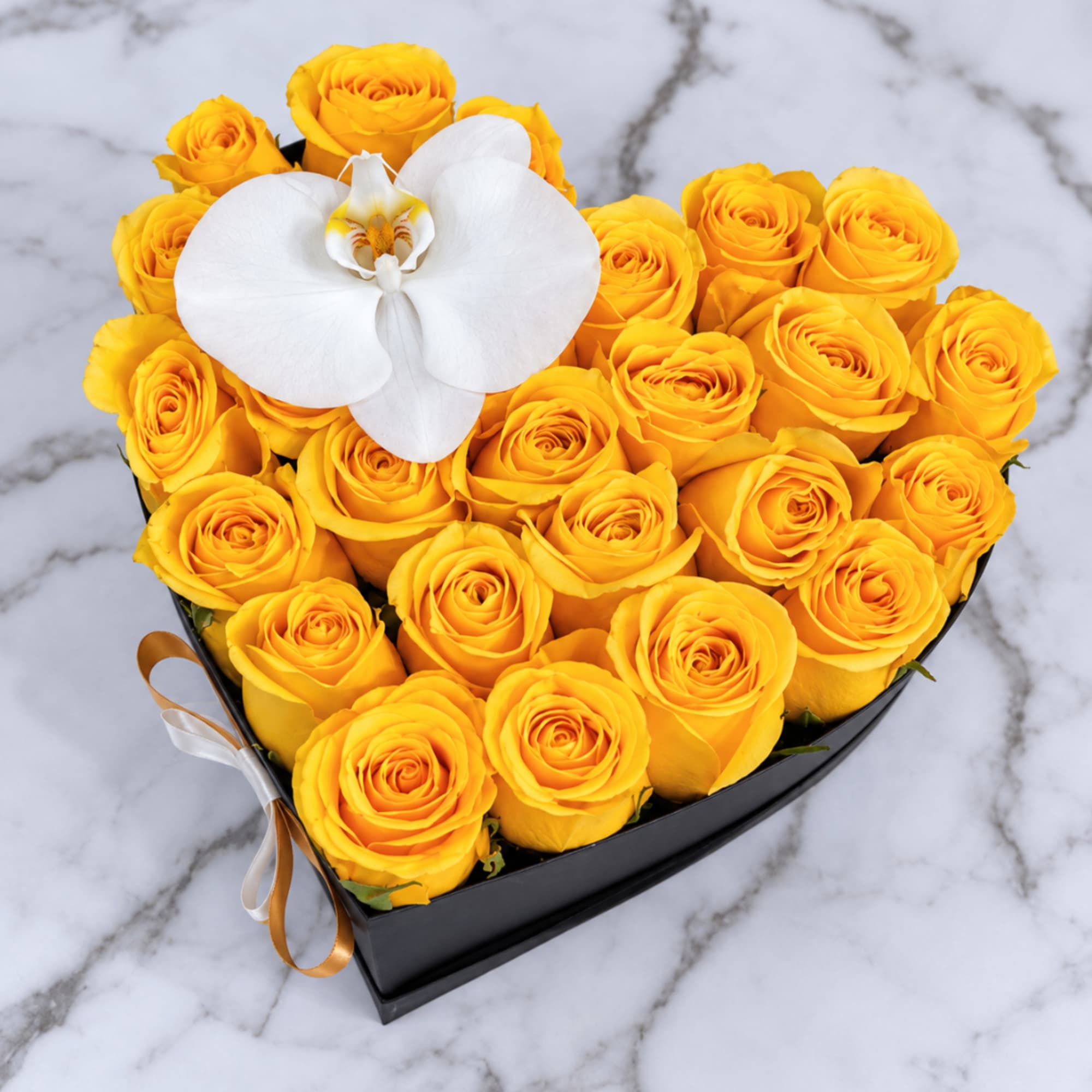 Heart-shaped box of yellow roses with a white orchid on top