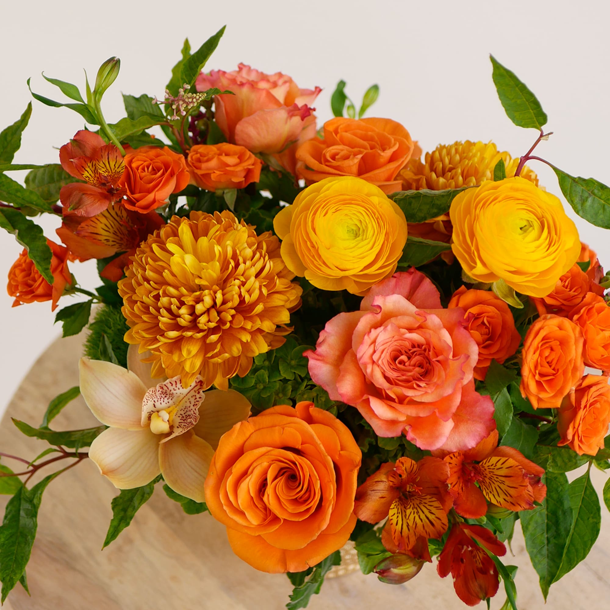 Orange and yellow mixed bouquet with roses, ranunculus, and orchids