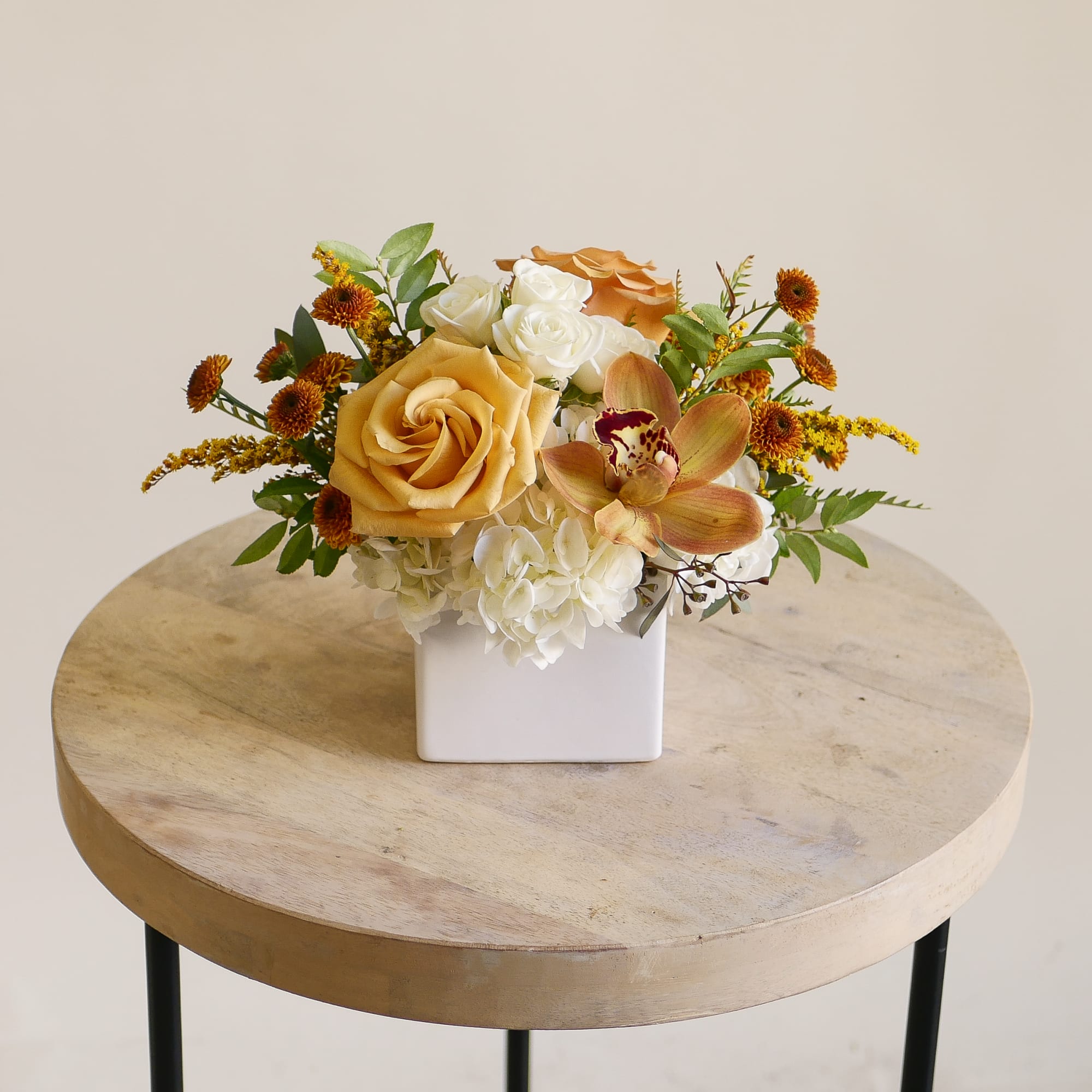 This petite Thanksgiving flower arrangement features soft cream roses and vibrant golden