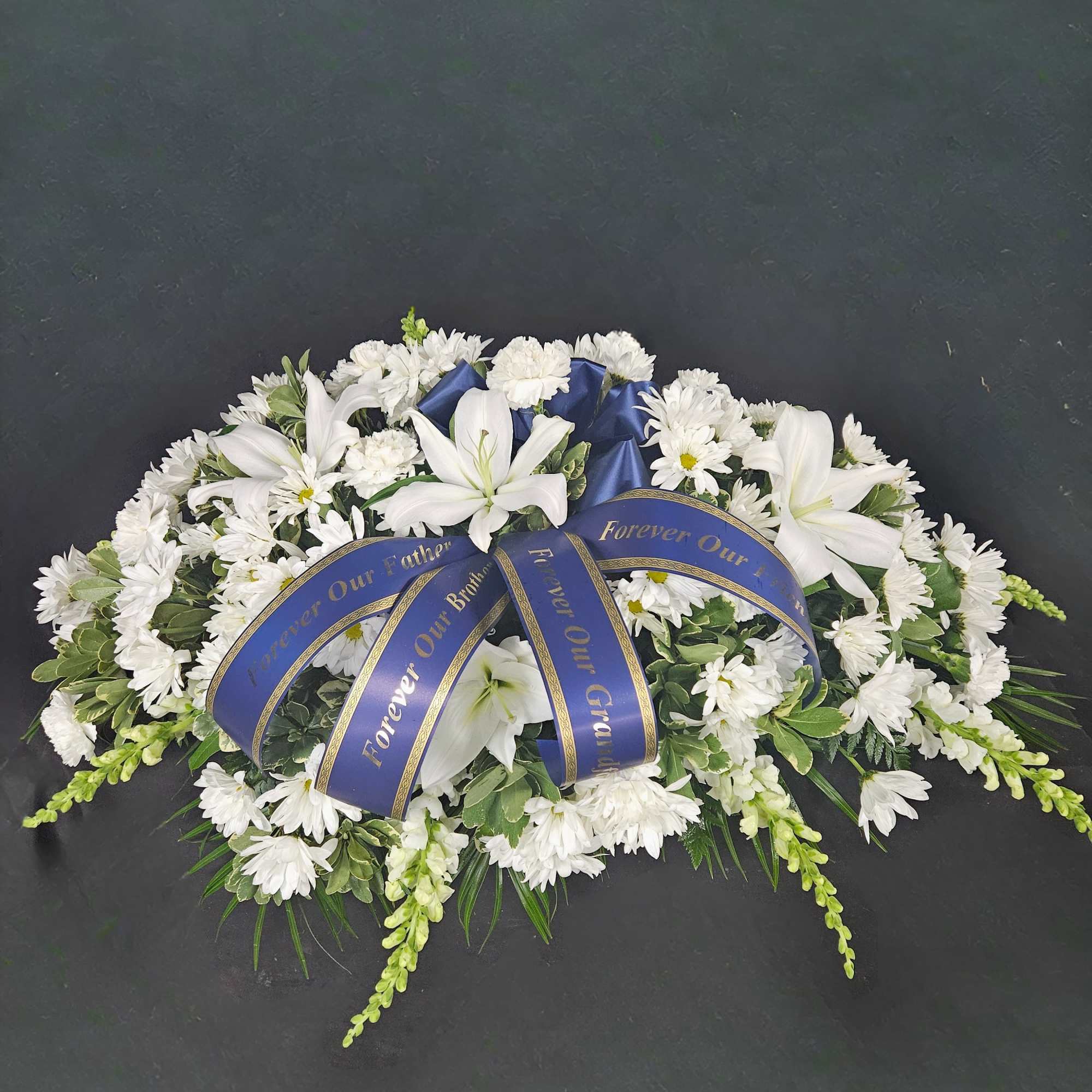 A bed of beautiful greenery is covered with white daisy poms and