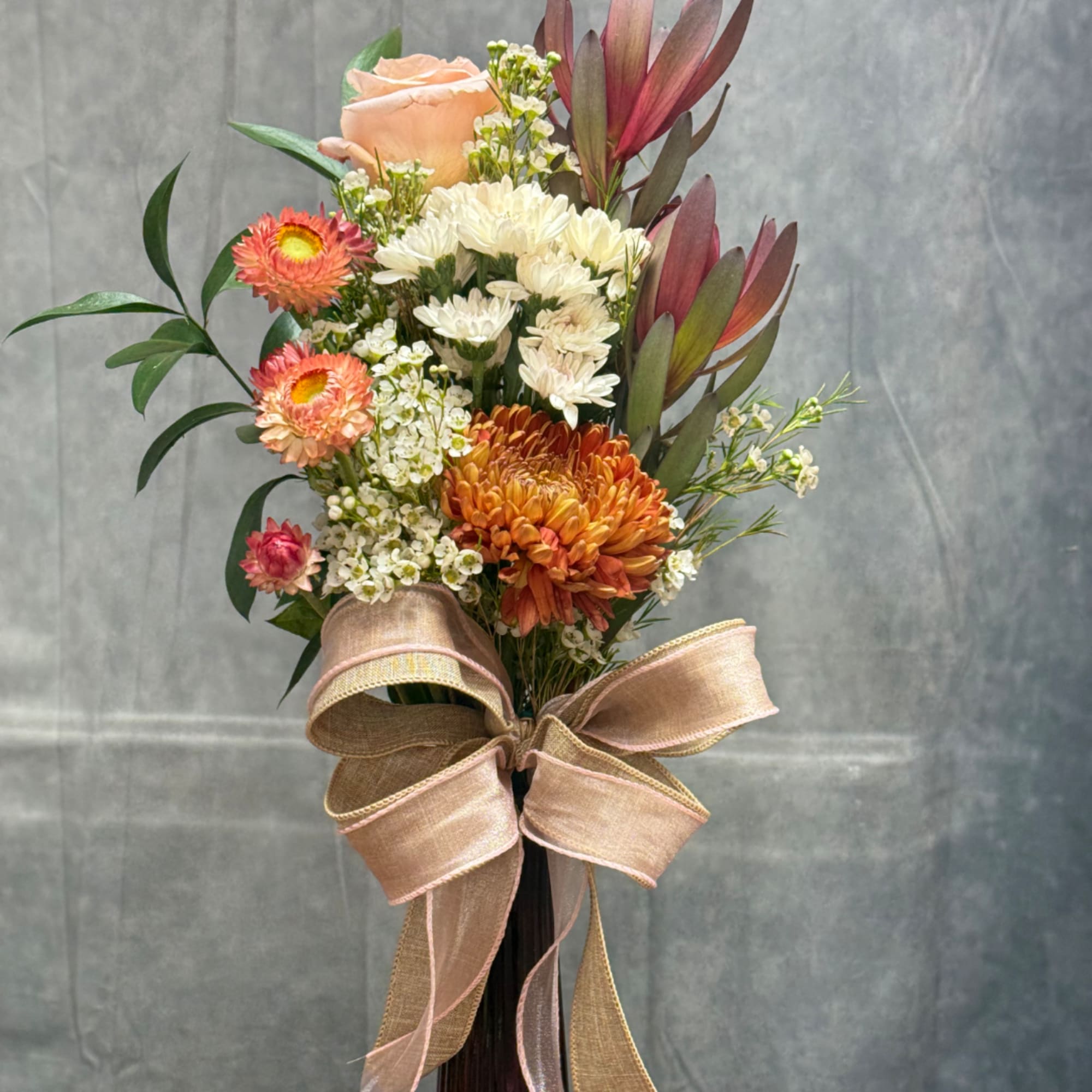 Bouquet of peach, white, and orange flowers with a large ribbon bow
