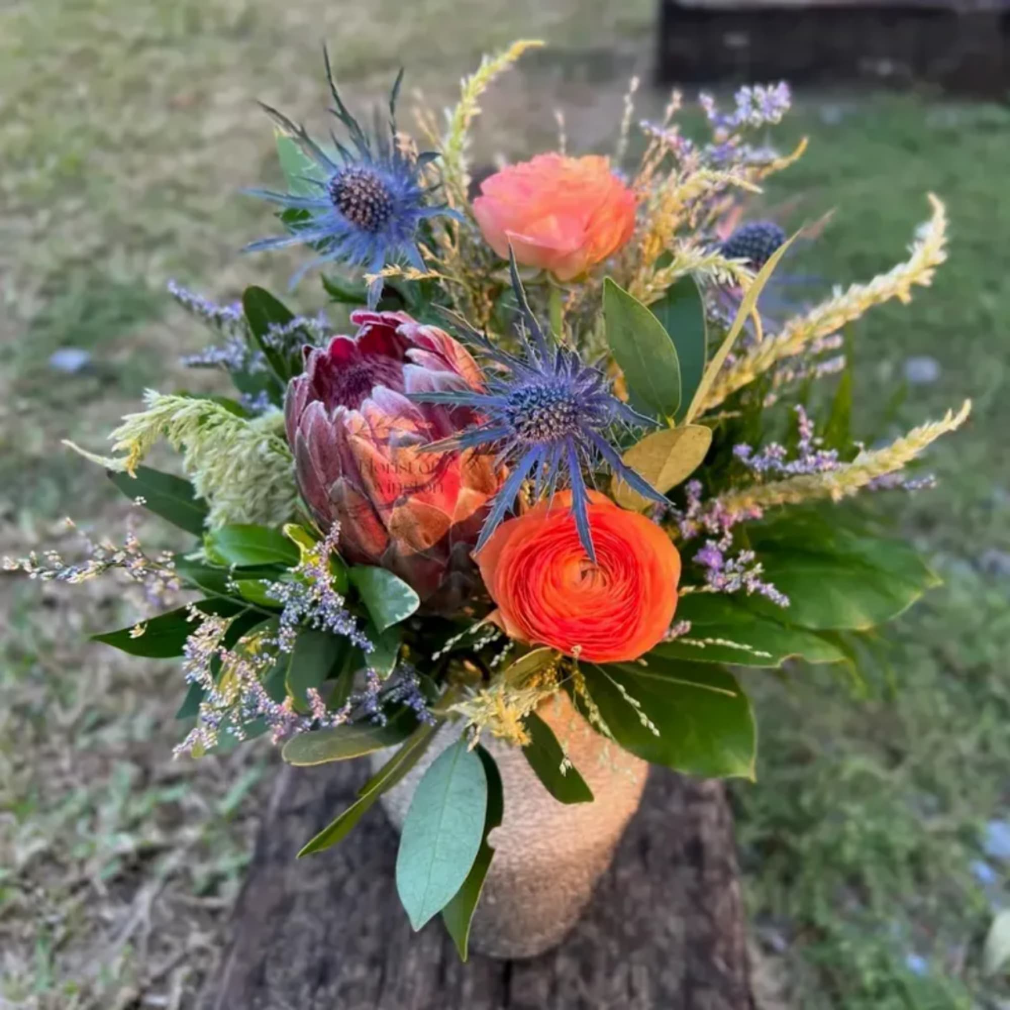 Mixed bouquet with orange and pink blooms in a textured vase