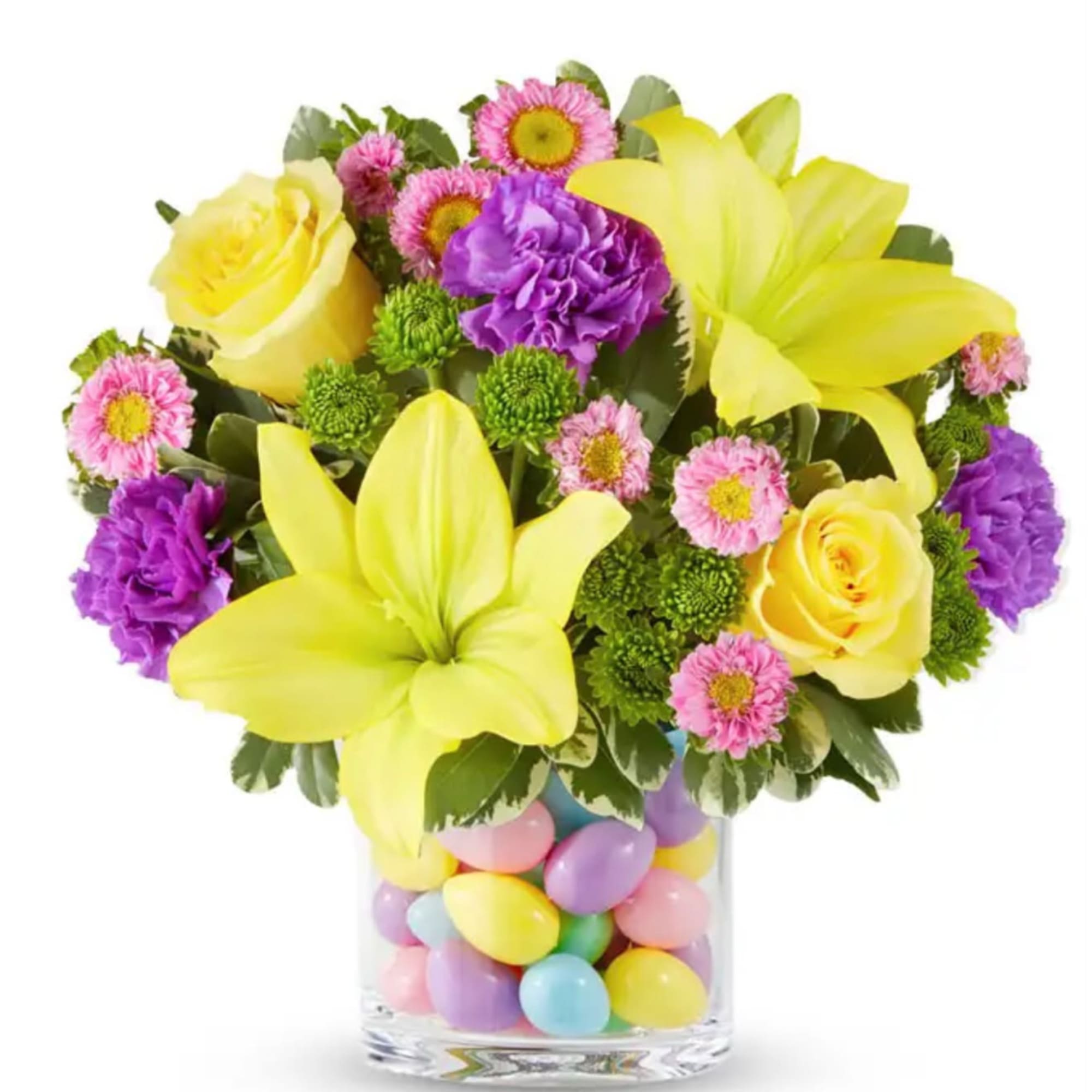 Yellow lilies, roses, and purple flowers in a glass vase filled with pastel eggs