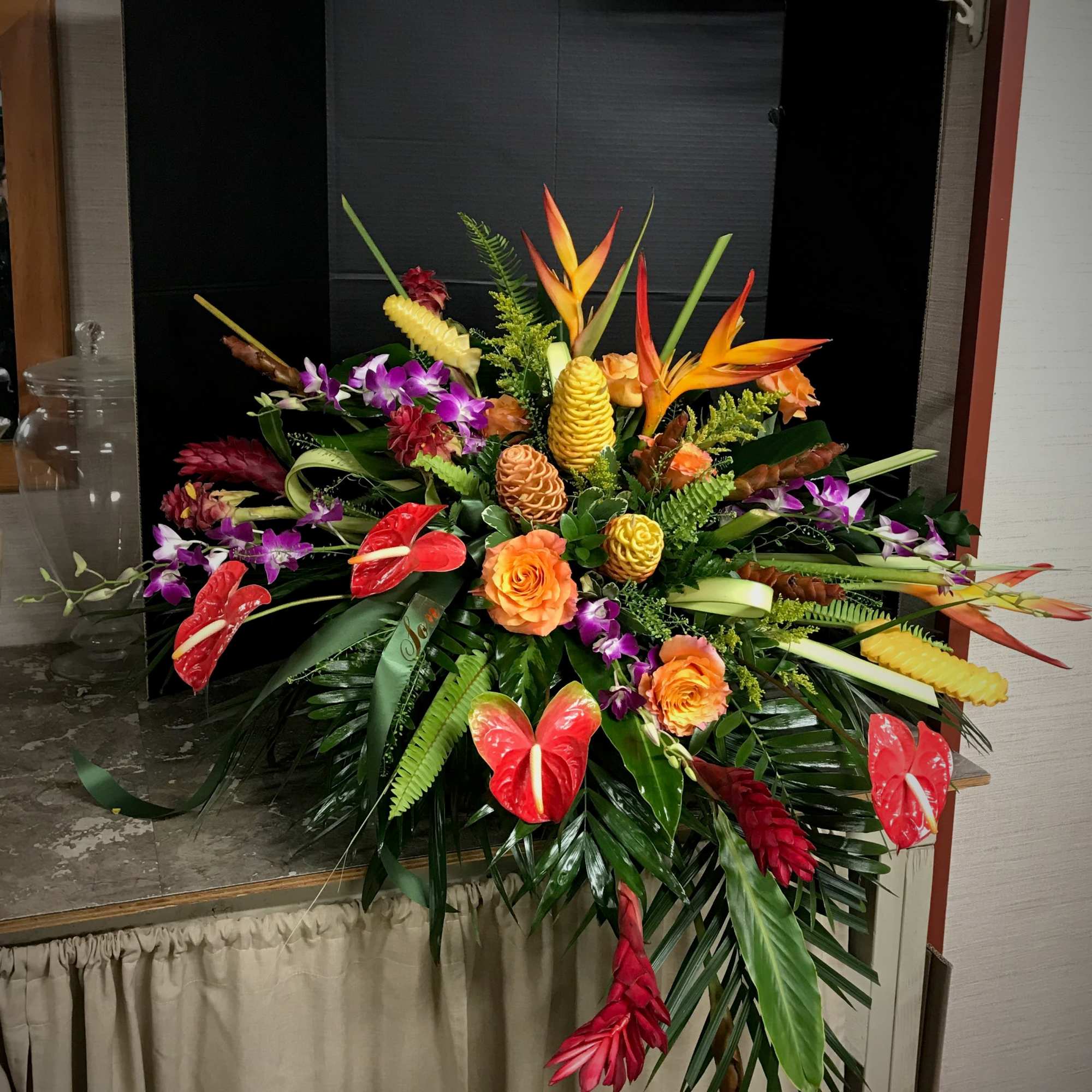 Large tropical floral arrangement with orange roses and orchids