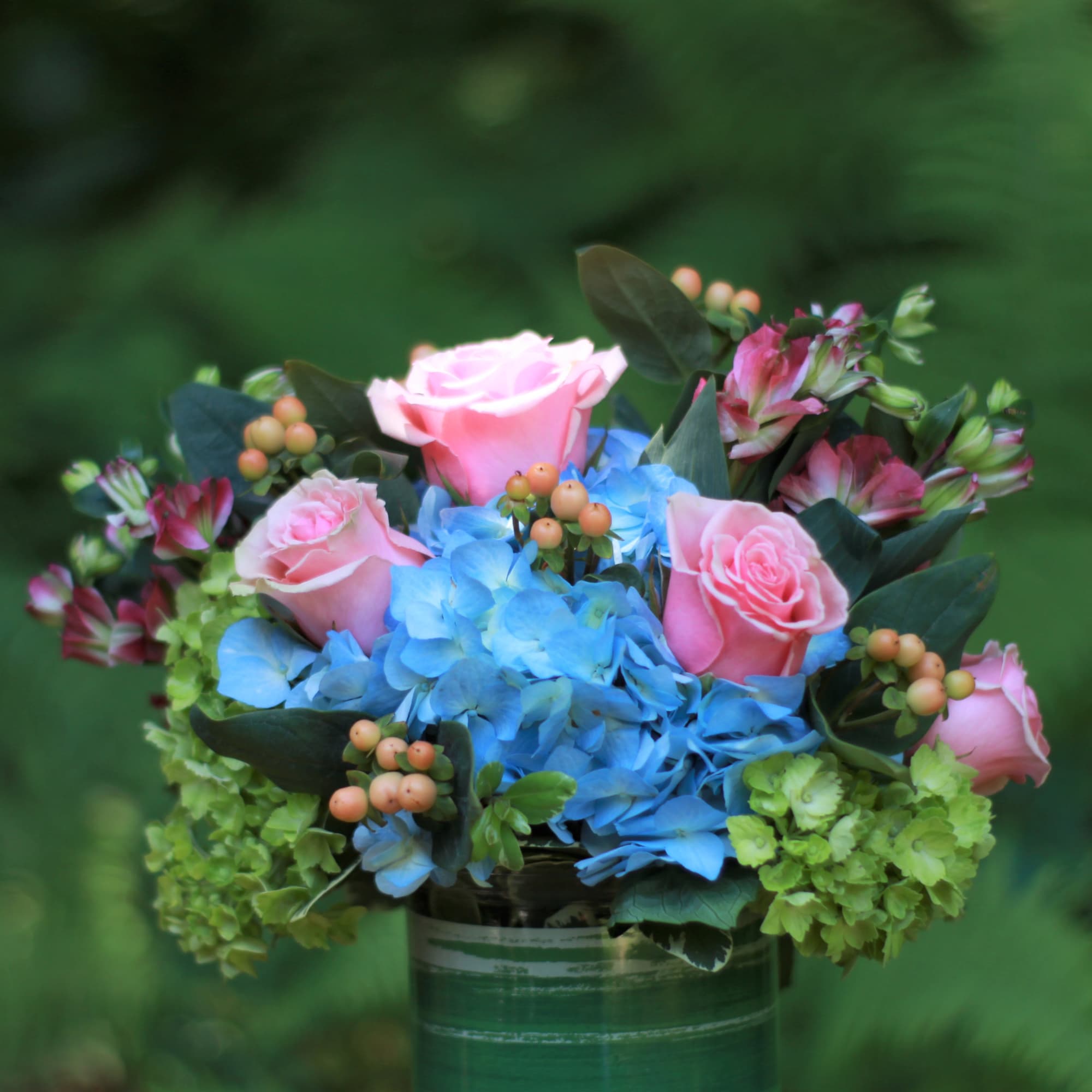 Pink roses and blue hydrangeas in a glass vase