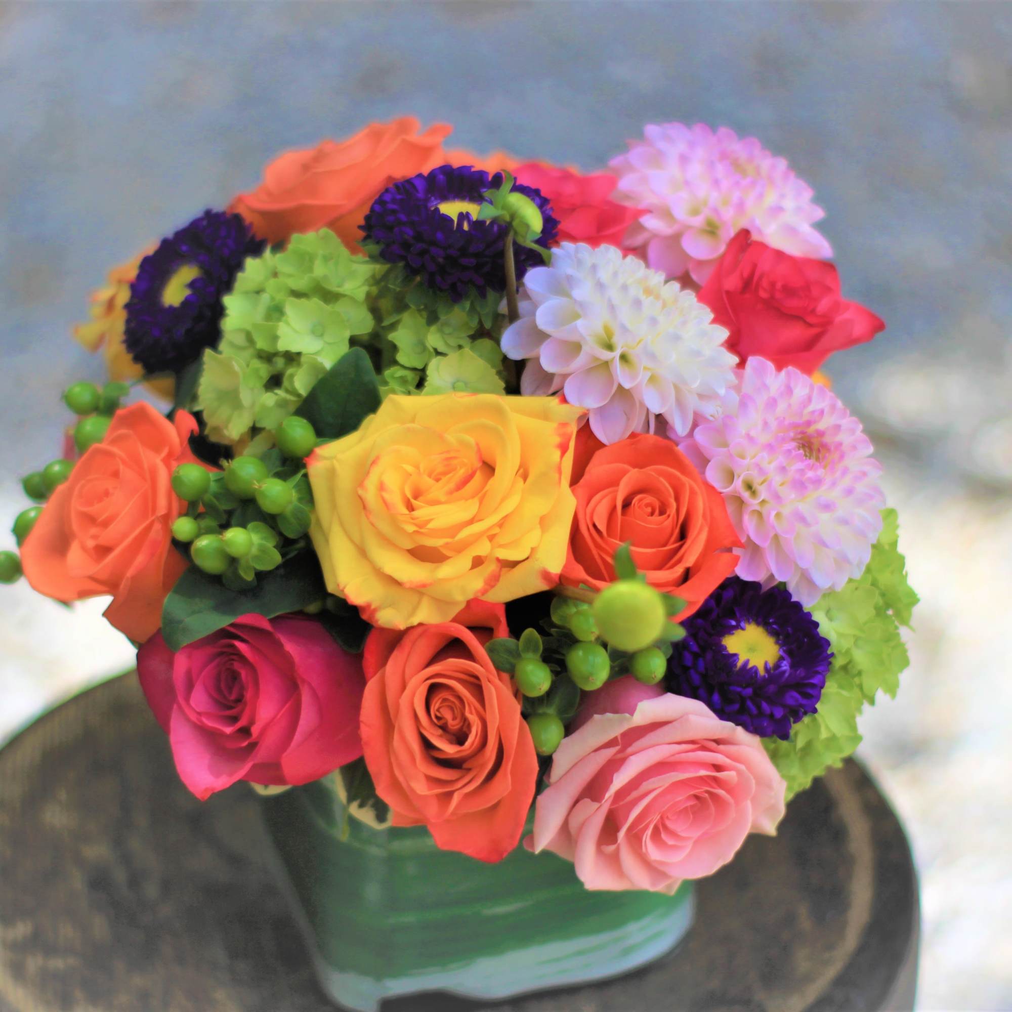 Colorful bouquet of roses and dahlias in a green vase