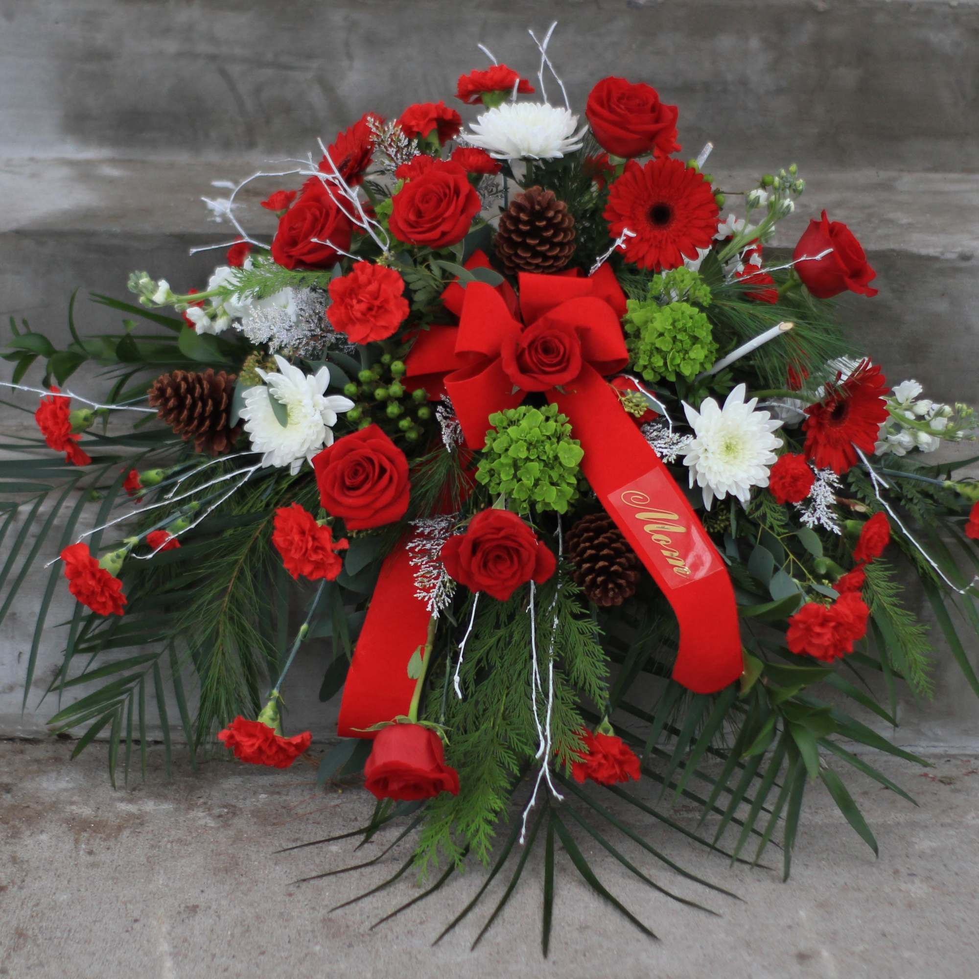 Red and white floral spray with roses, daisies, and ribbon