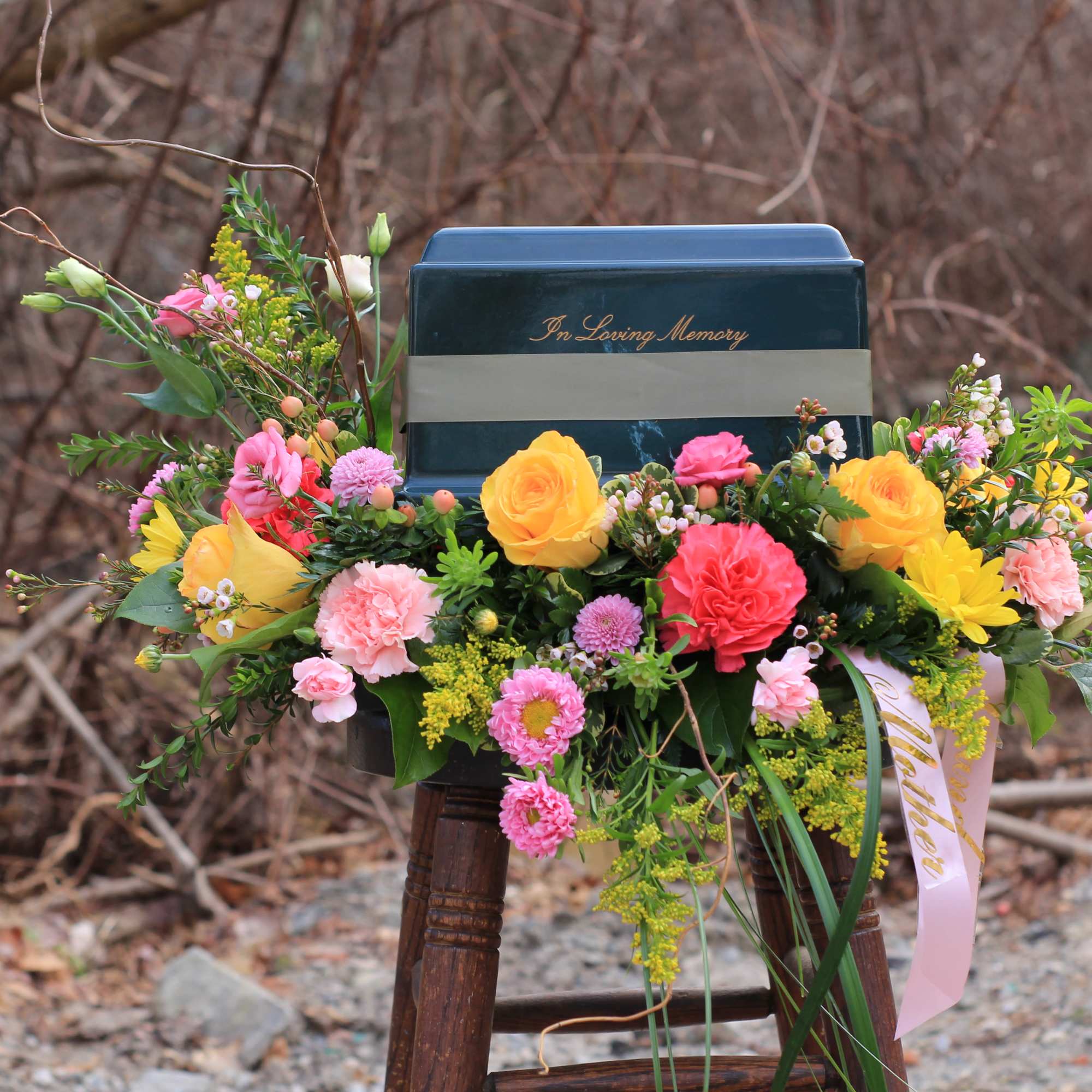 Floral arrangement around a memorial urn with pink and yellow flowers