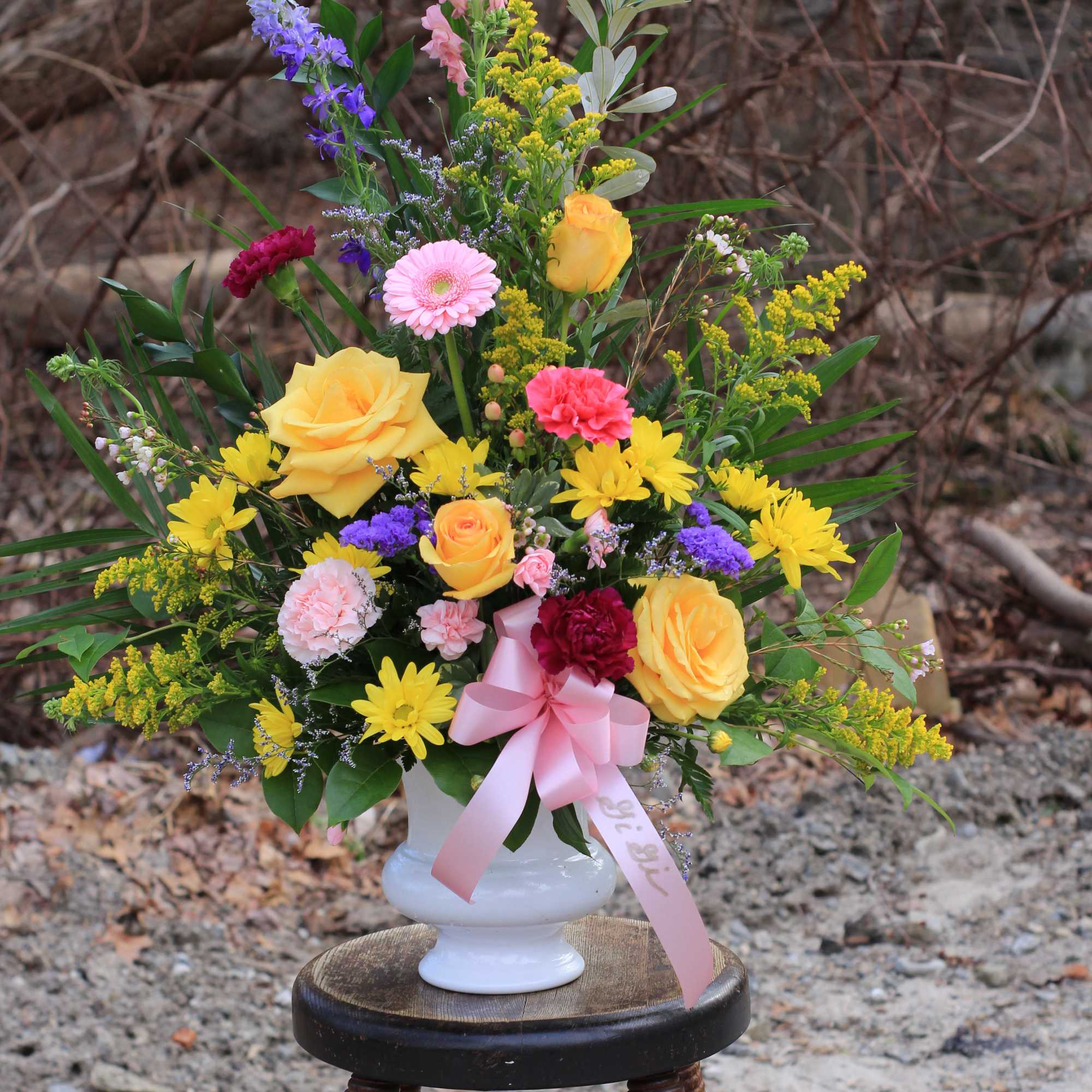 Colorful mixed bouquet in a white vase with a pink ribbon