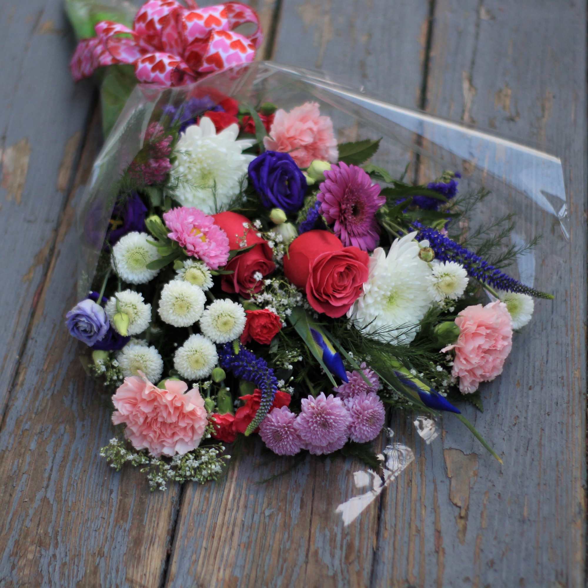 Mixed bouquet of roses, carnations, and daisies wrapped in clear plastic, photo 2 of 2