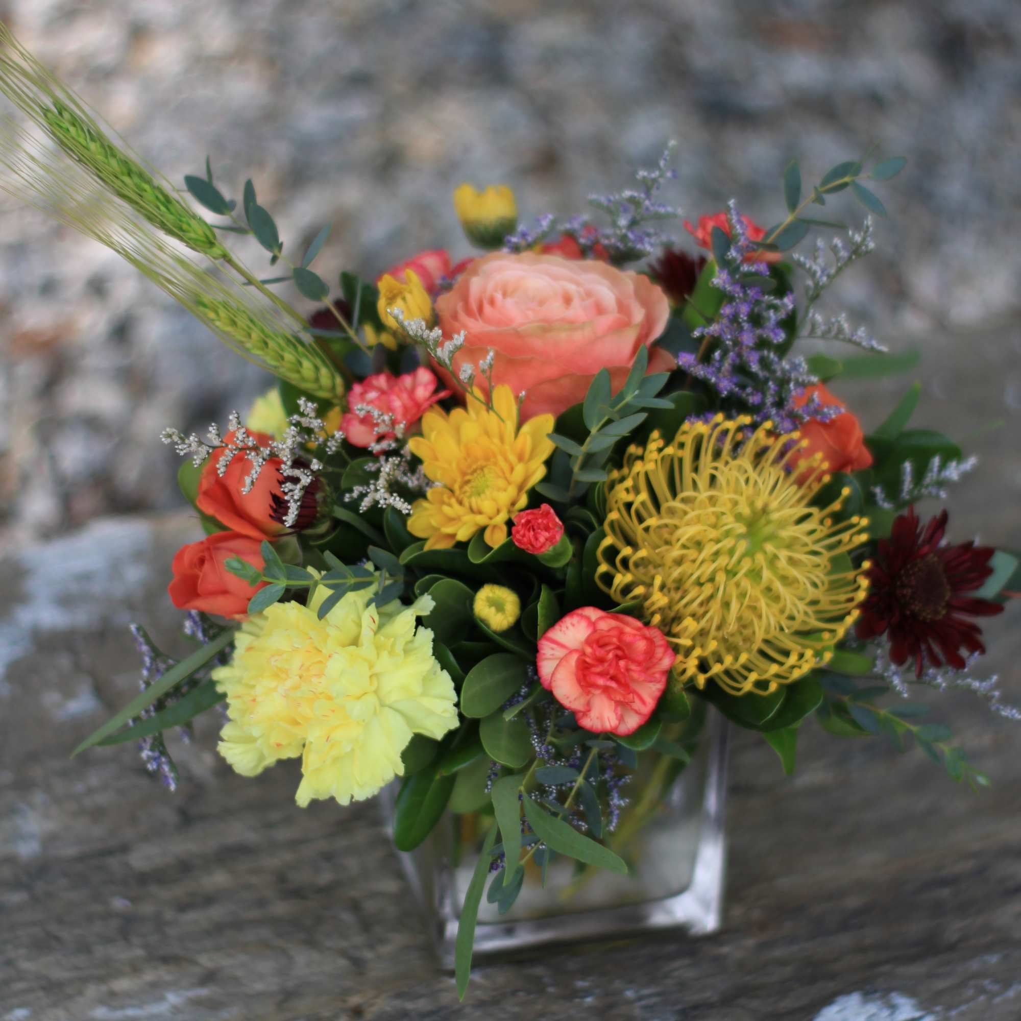 Mixed bouquet of colorful flowers in a clear square vase