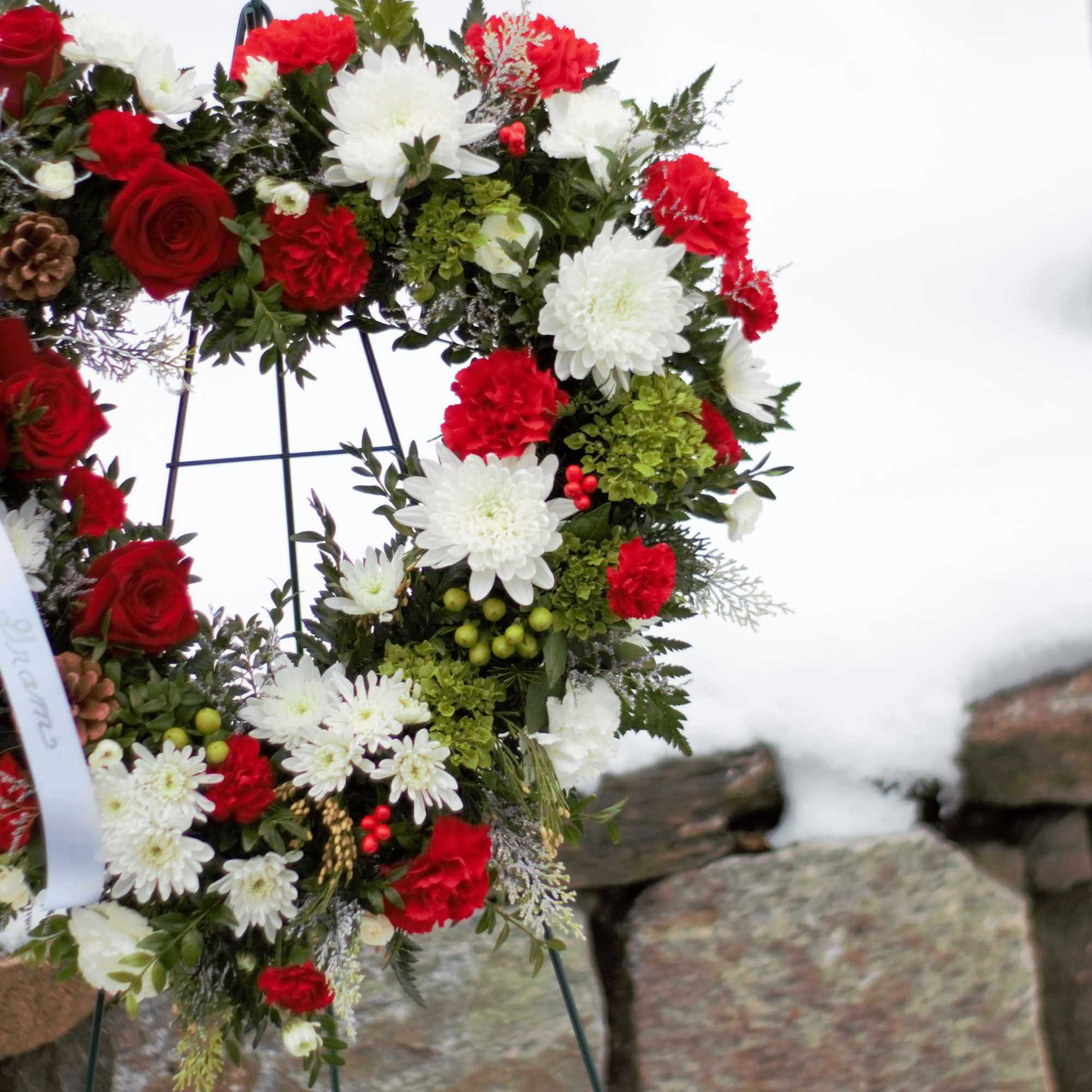 Red and white floral wreath on a black stand