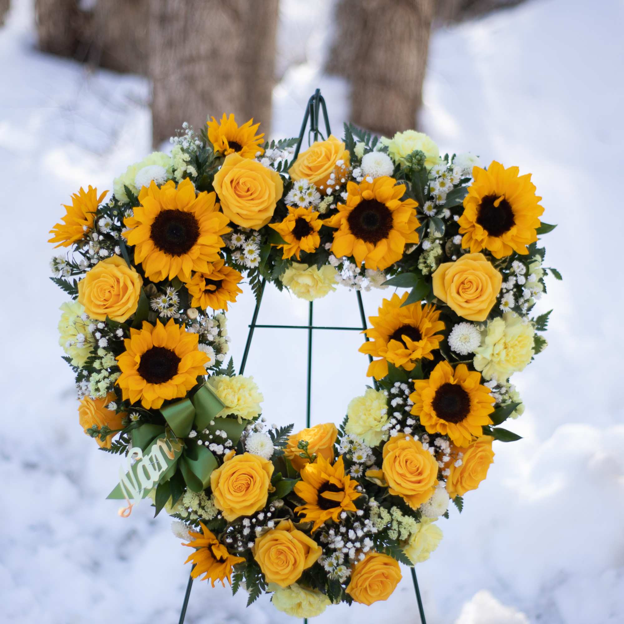 Heart-shaped wreath of yellow roses and sunflowers on a stand