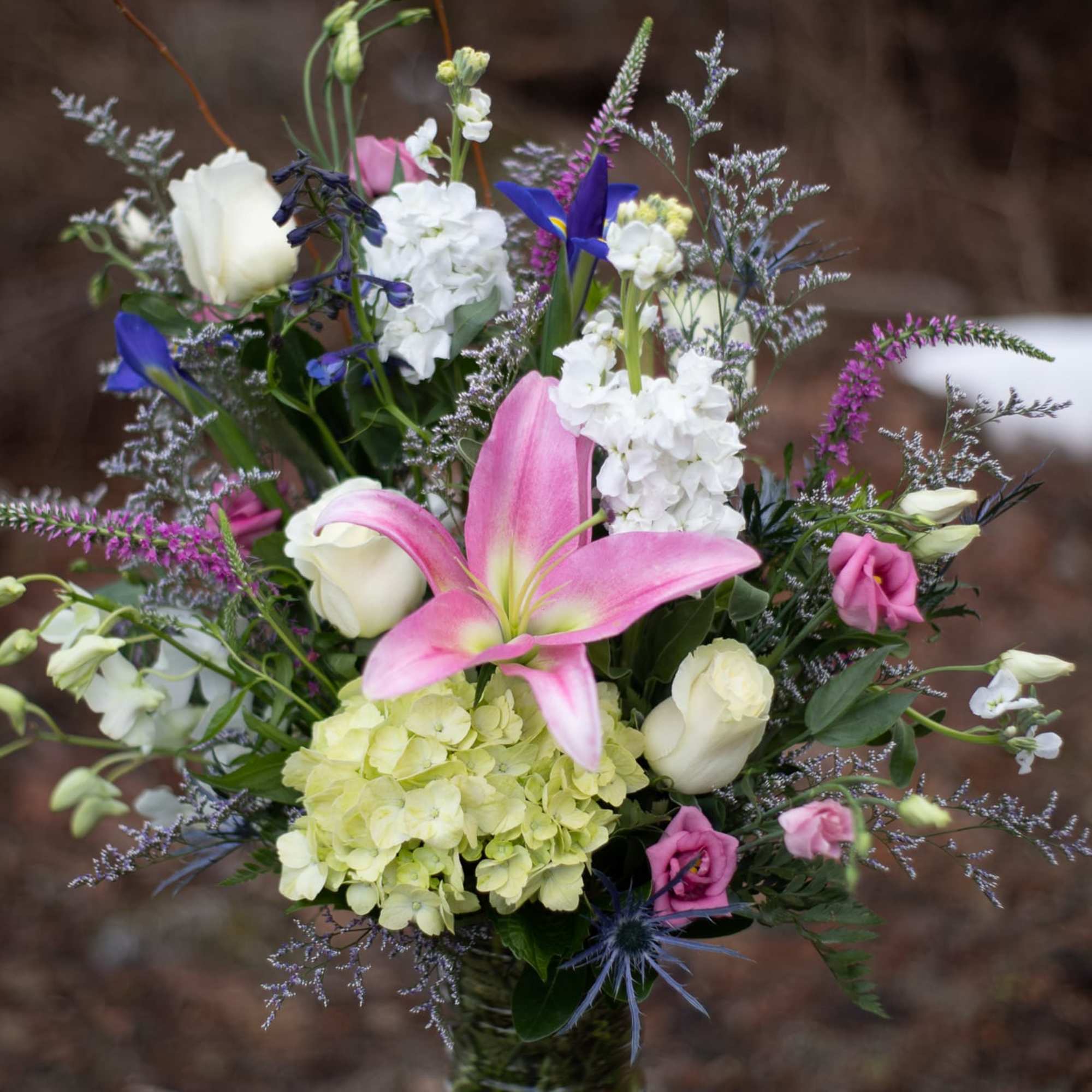 Bouquet of pink lilies, white roses, and purple flowers in a vase