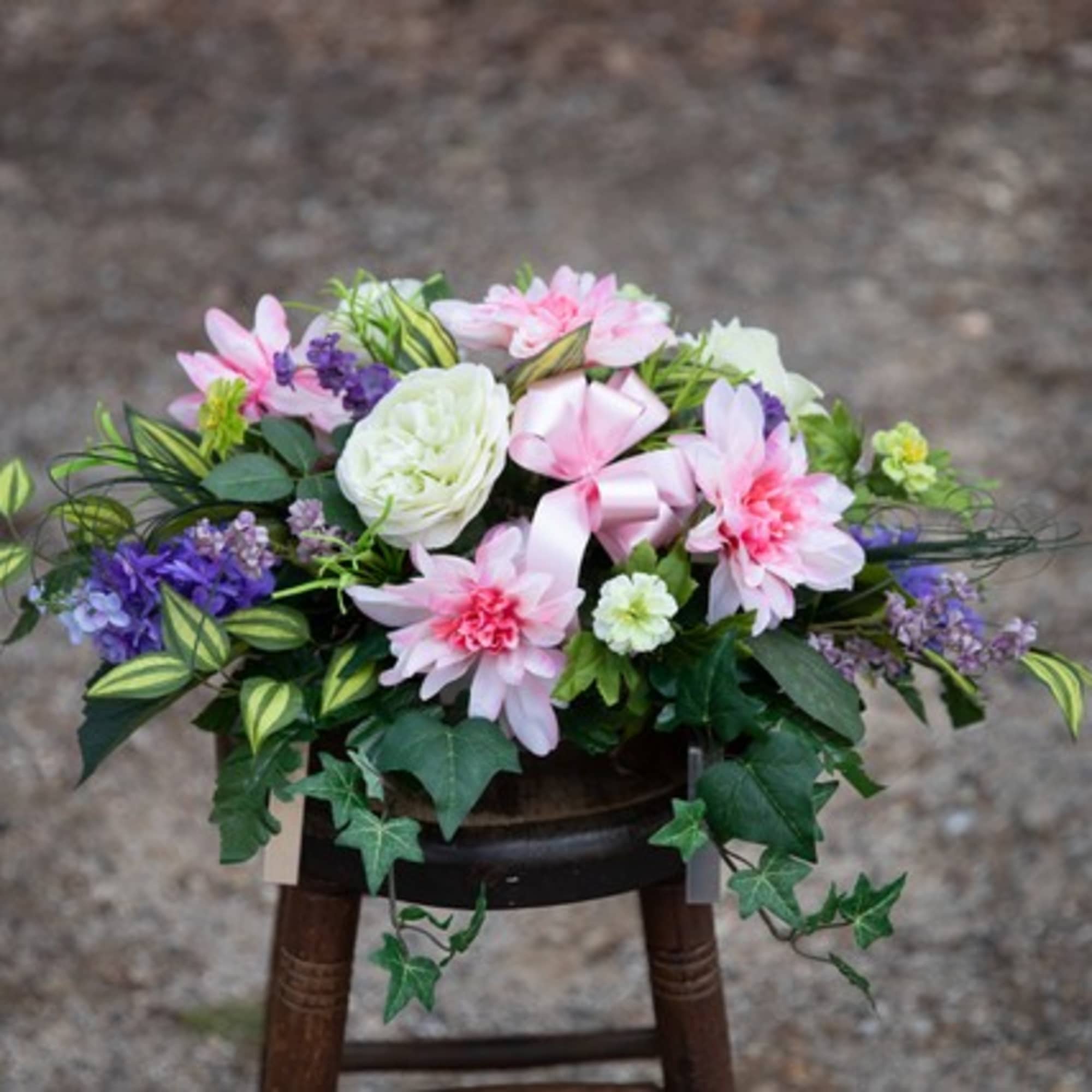 Pink and white floral arrangement with purple accents in a low container