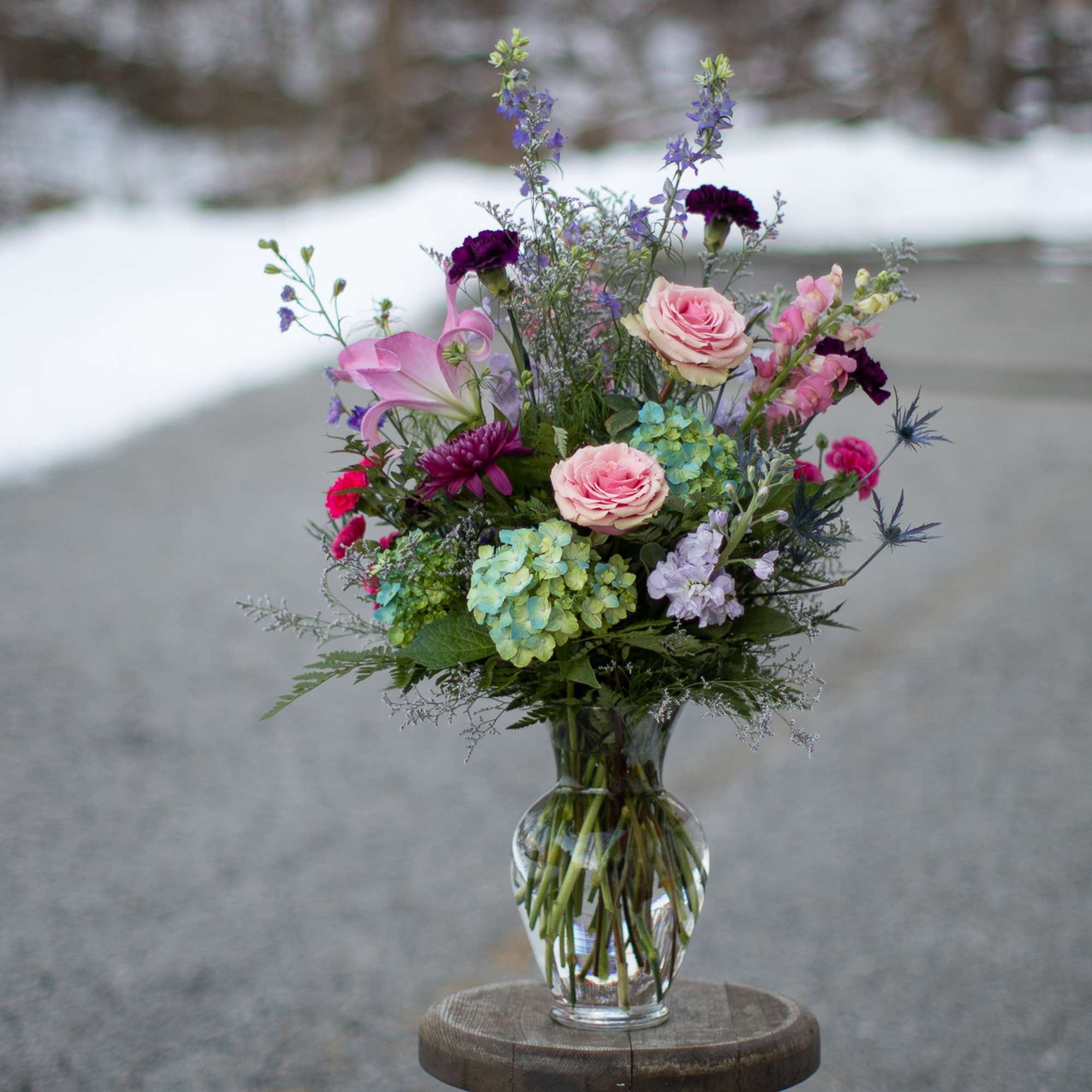 Mixed bouquet of pink roses and purple flowers in a glass vase