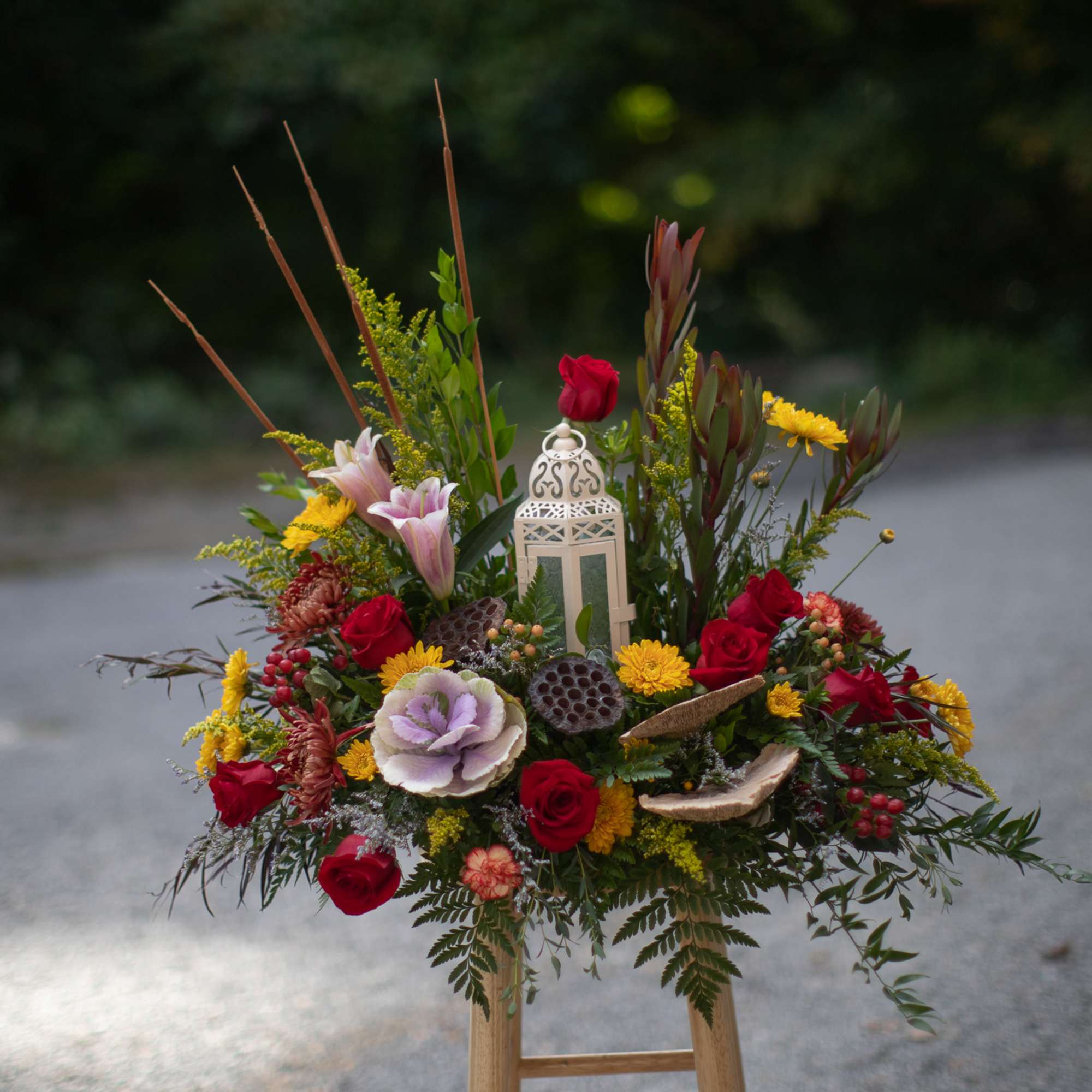Mixed floral arrangement with roses, lilies, and a lantern centerpiece