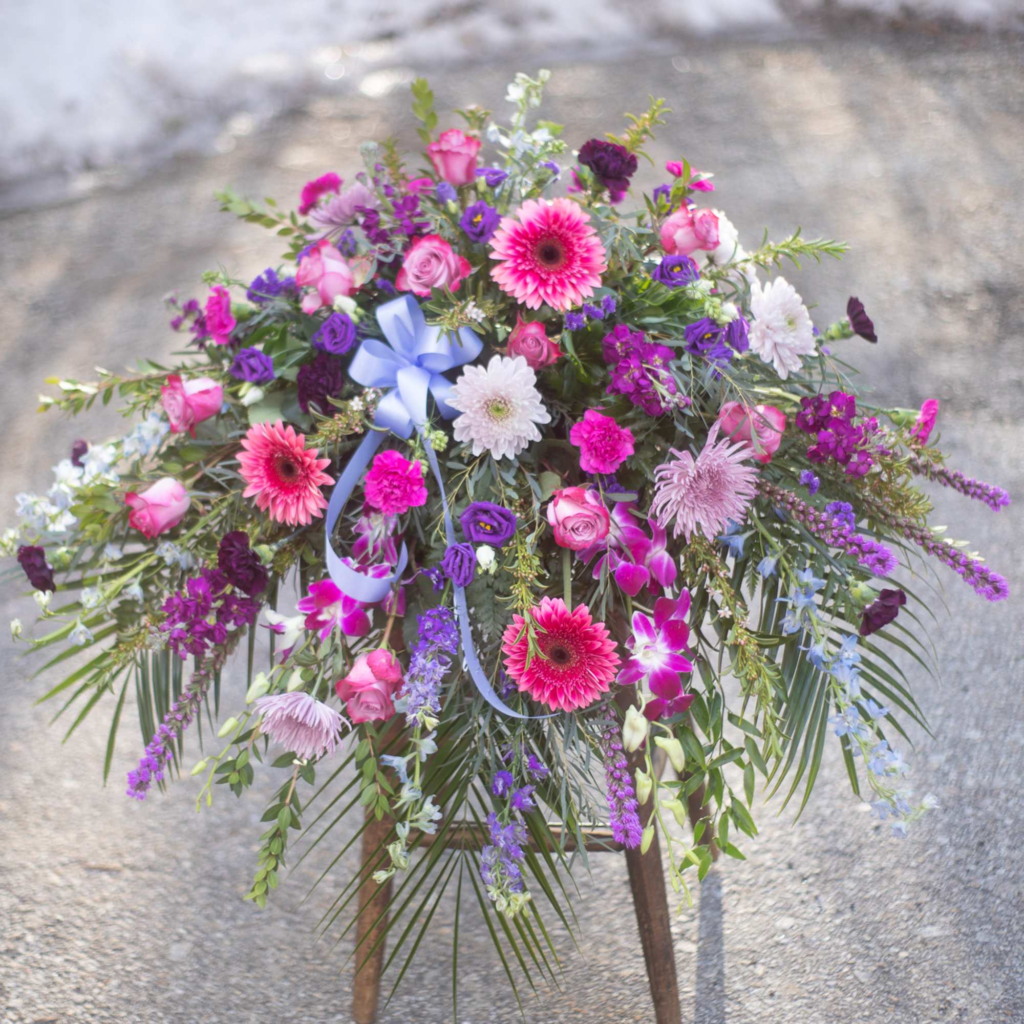 Large standing floral spray with pink, purple, and white blooms on a wooden easel