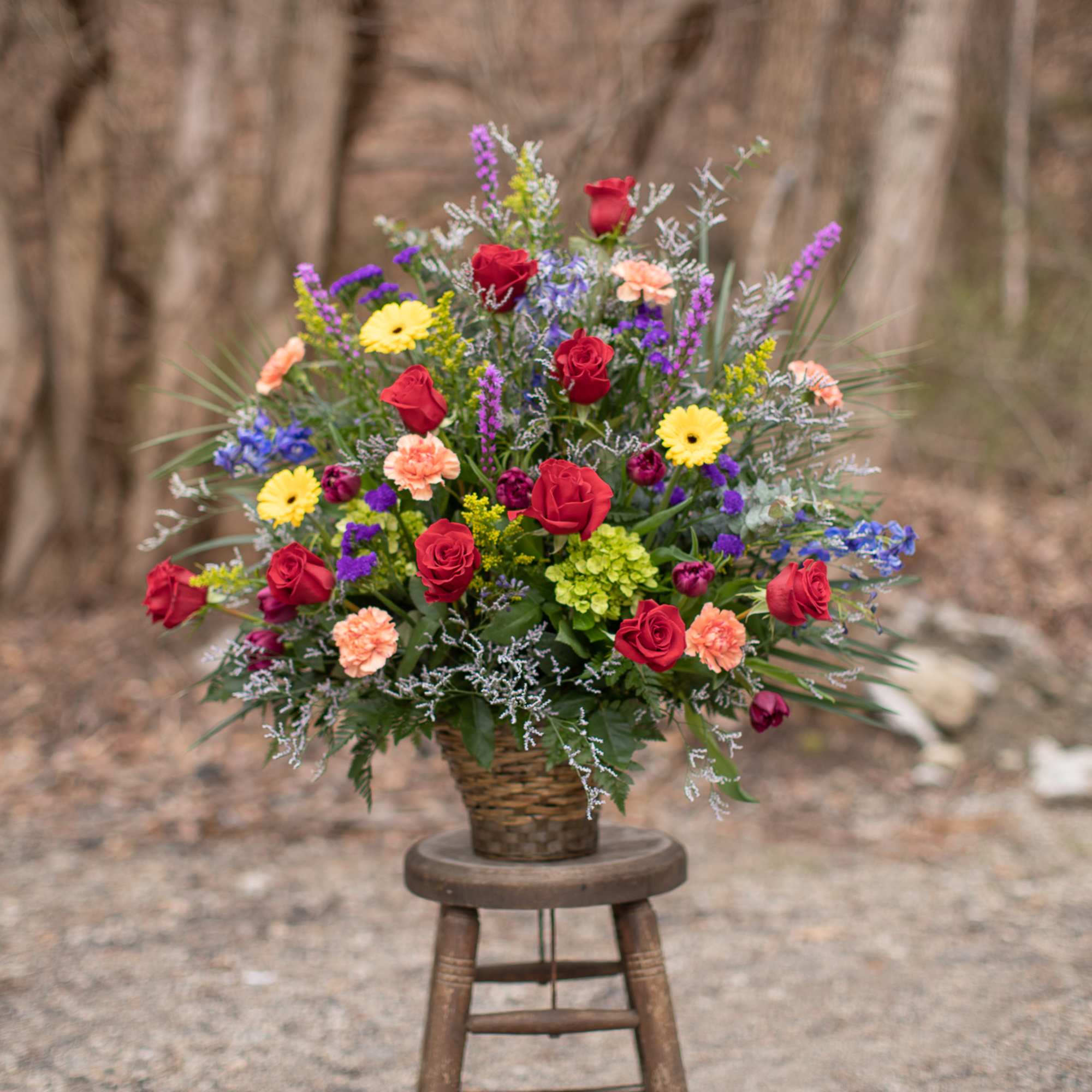Mixed bouquet of roses, daisies, and carnations in a woven basket