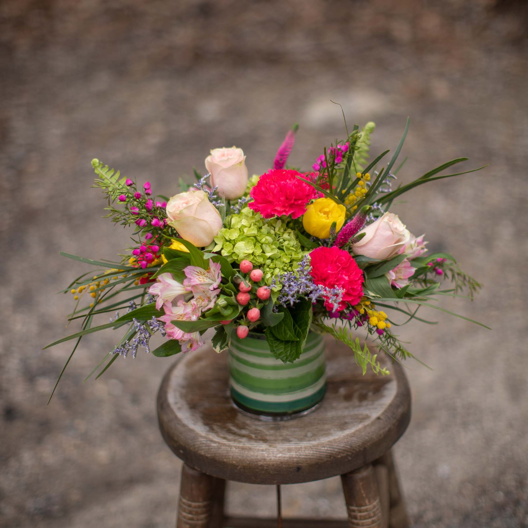 Mixed bouquet in a striped glass vase with pink roses and bright carnations