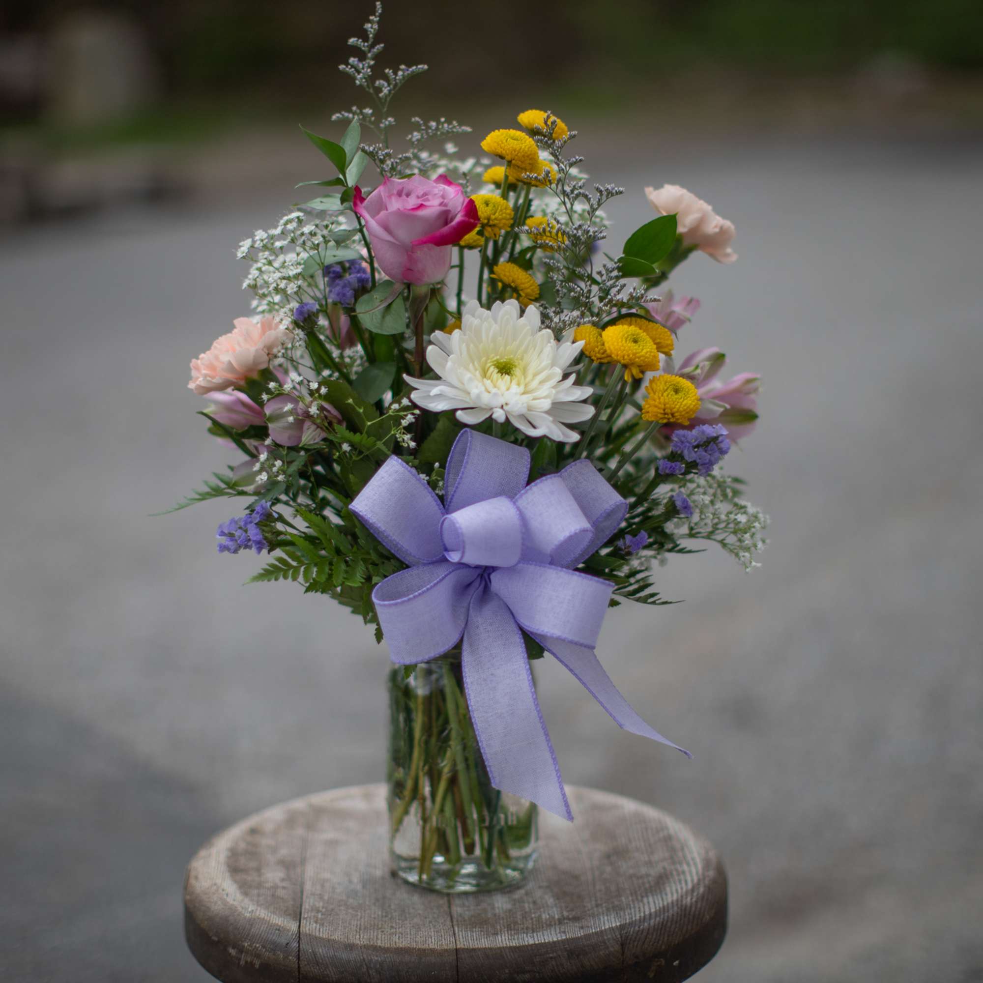 Mixed bouquet in a glass vase with a lavender ribbon