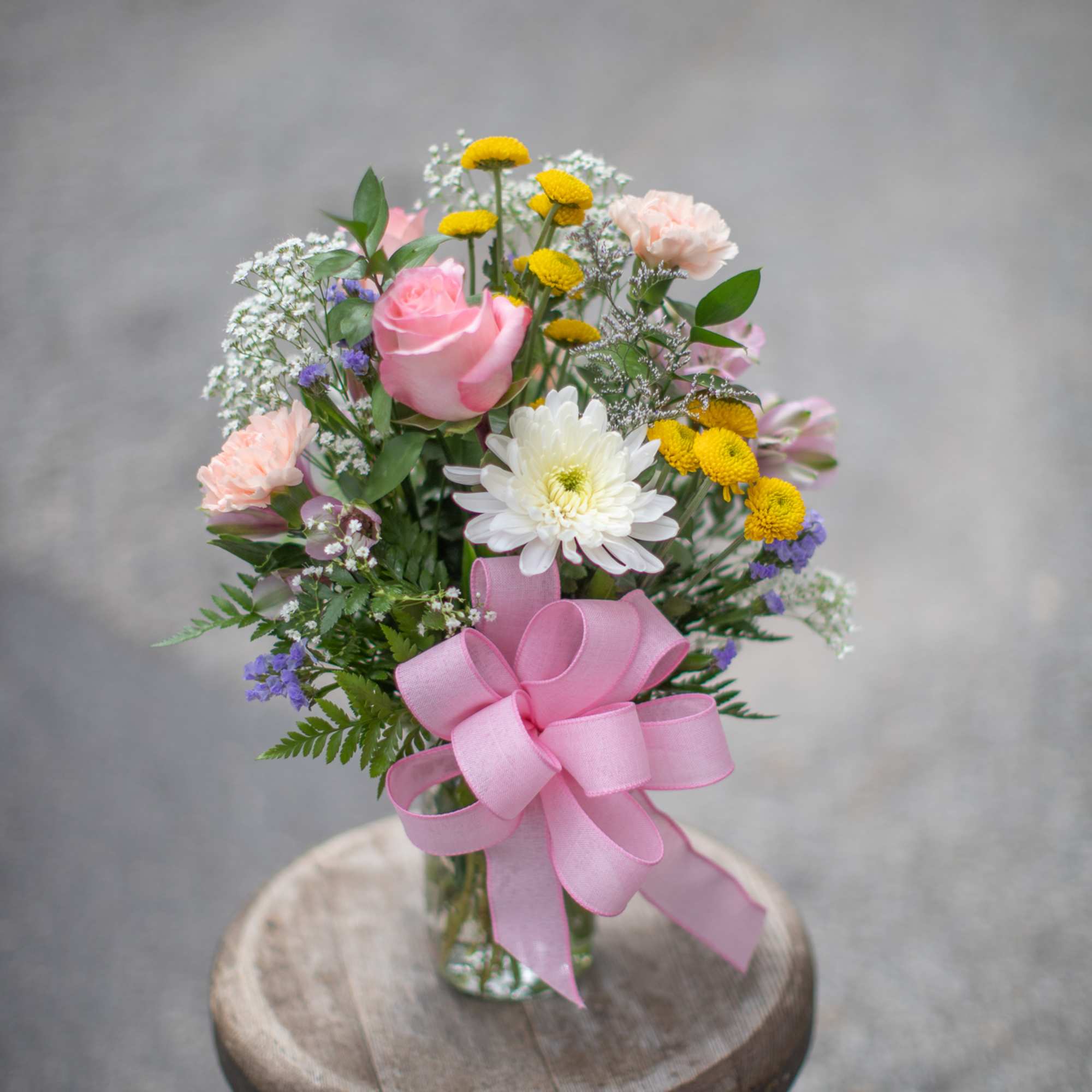 Small mixed bouquet in a glass vase with a pink ribbon