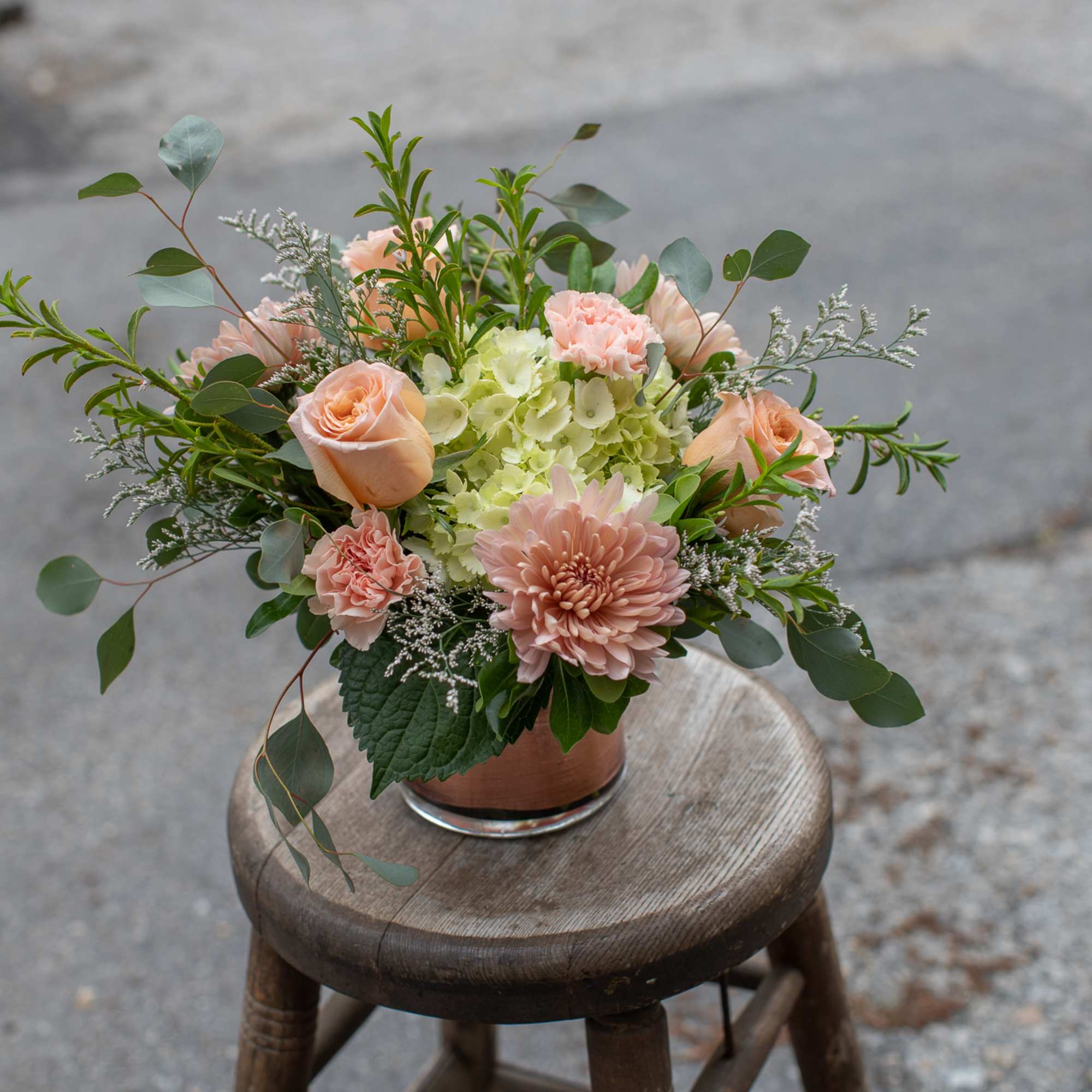 Peach roses and pink blooms in a low glass vase