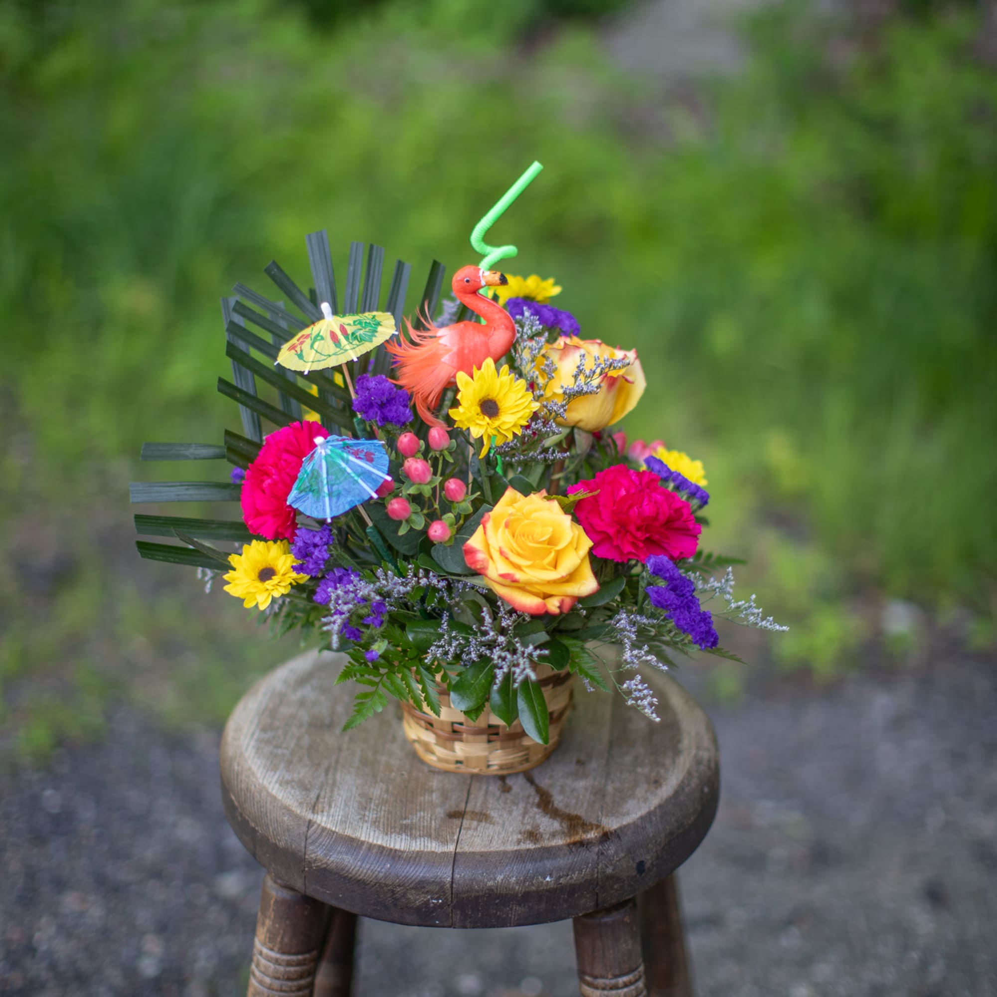 Basket arrangement with bright flowers and a flamingo decoration