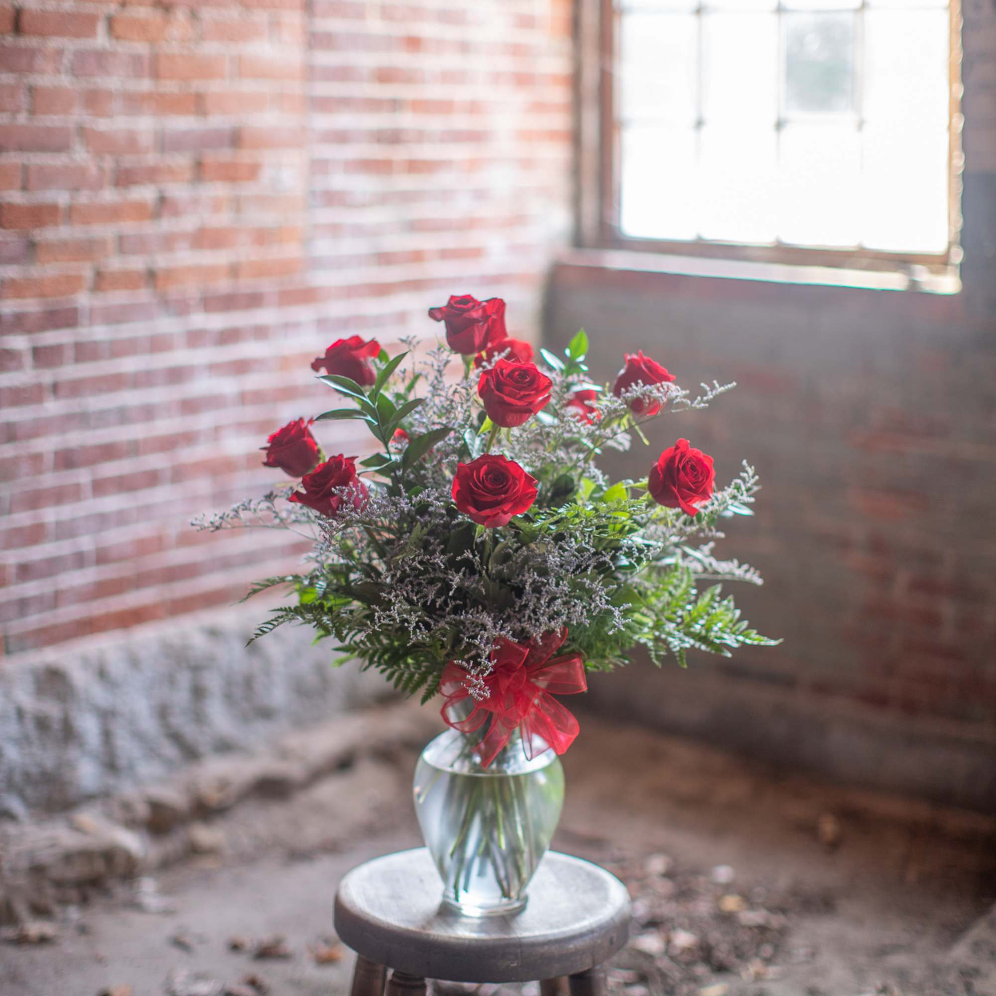 Red roses arranged in a clear glass vase with a red ribbon.
