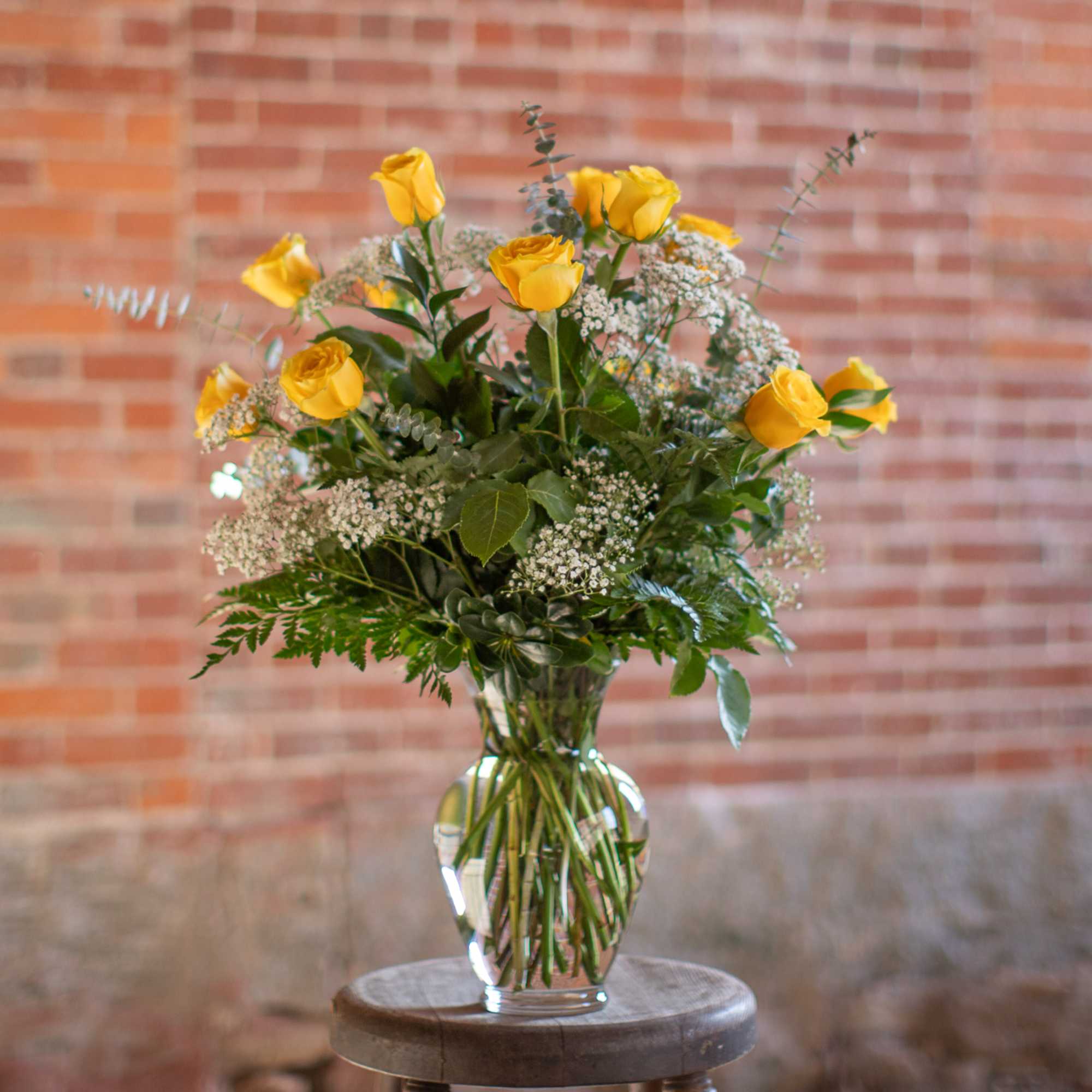 Yellow roses in a clear glass vase with baby's breath