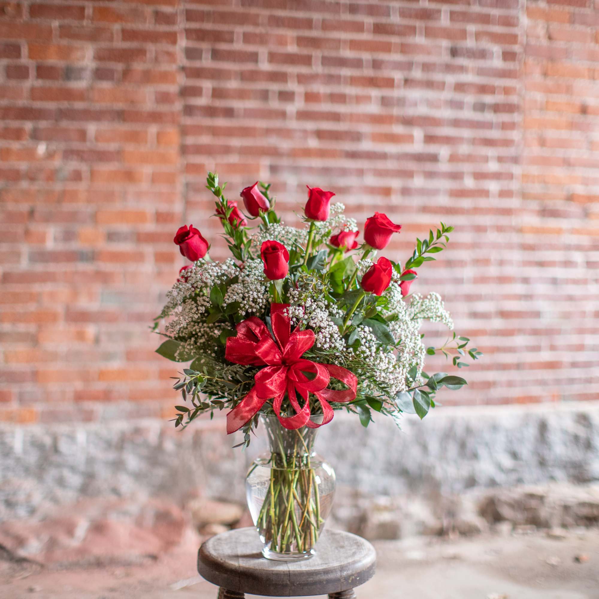 Bouquet of red roses in a clear glass vase with a red ribbon