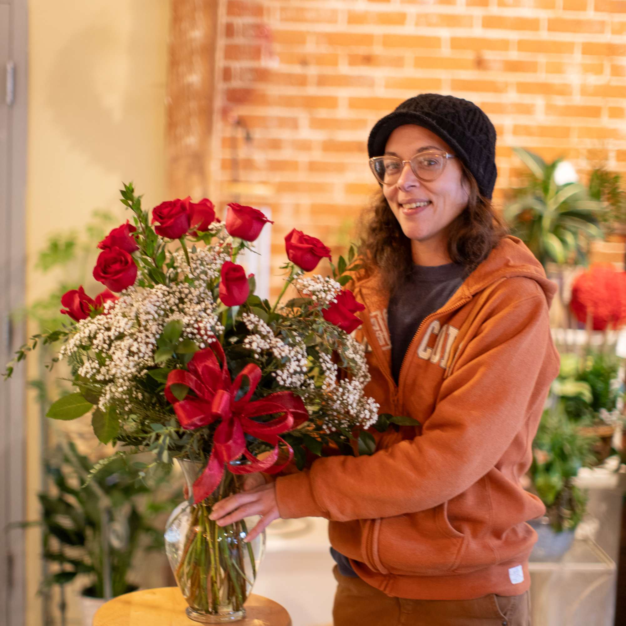 Woman holding a vase of red roses with a red ribbon