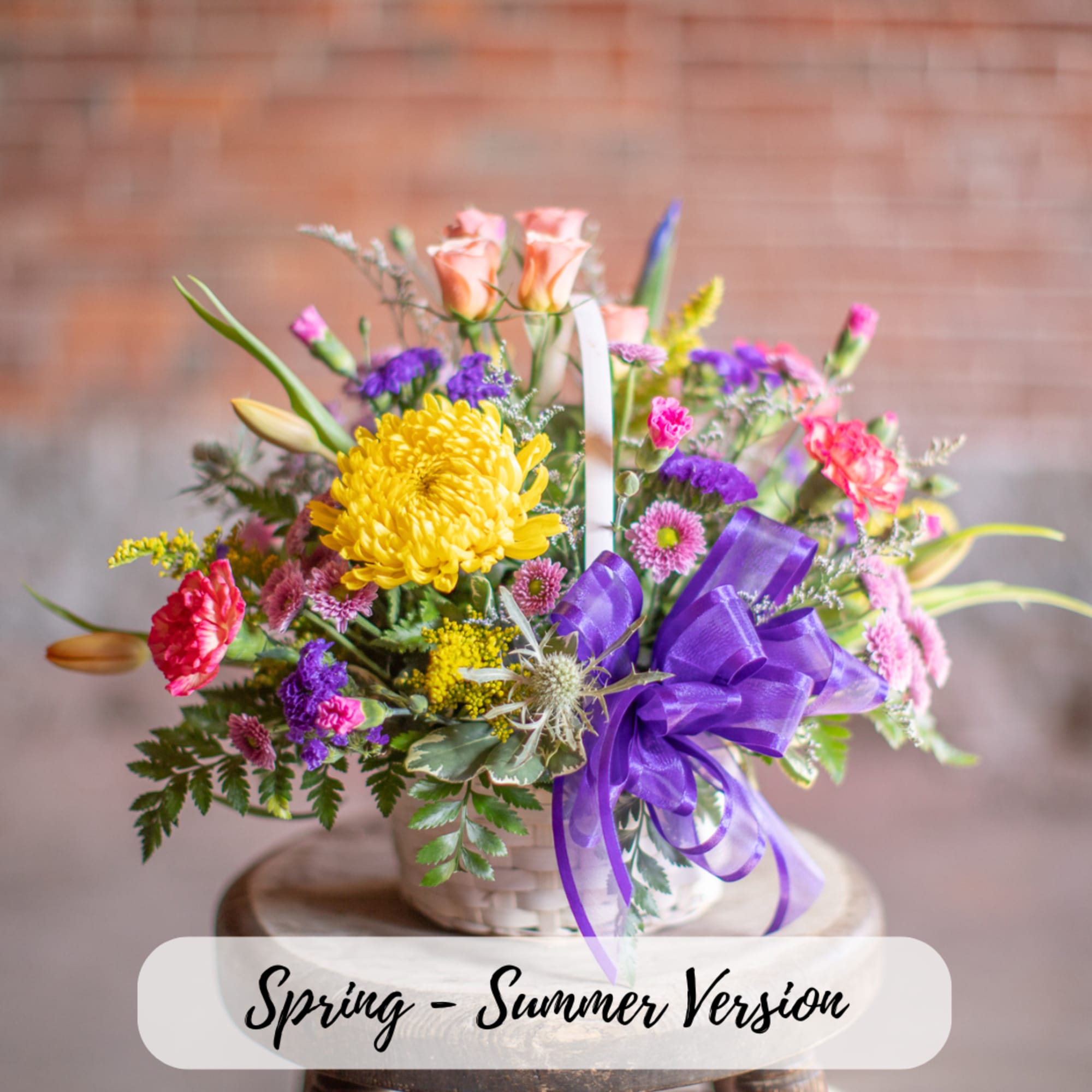 Mixed bouquet in a white basket with a purple ribbon