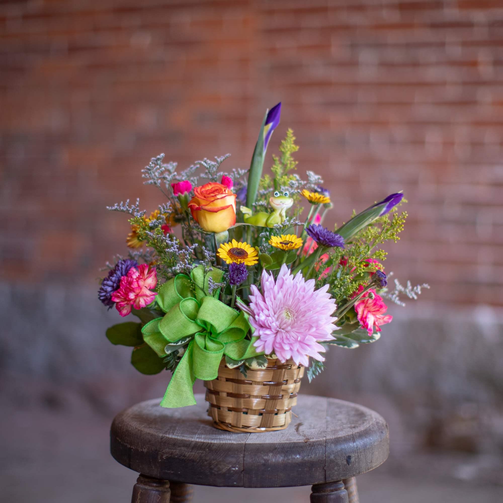 Mixed bouquet in a small woven basket with a green ribbon