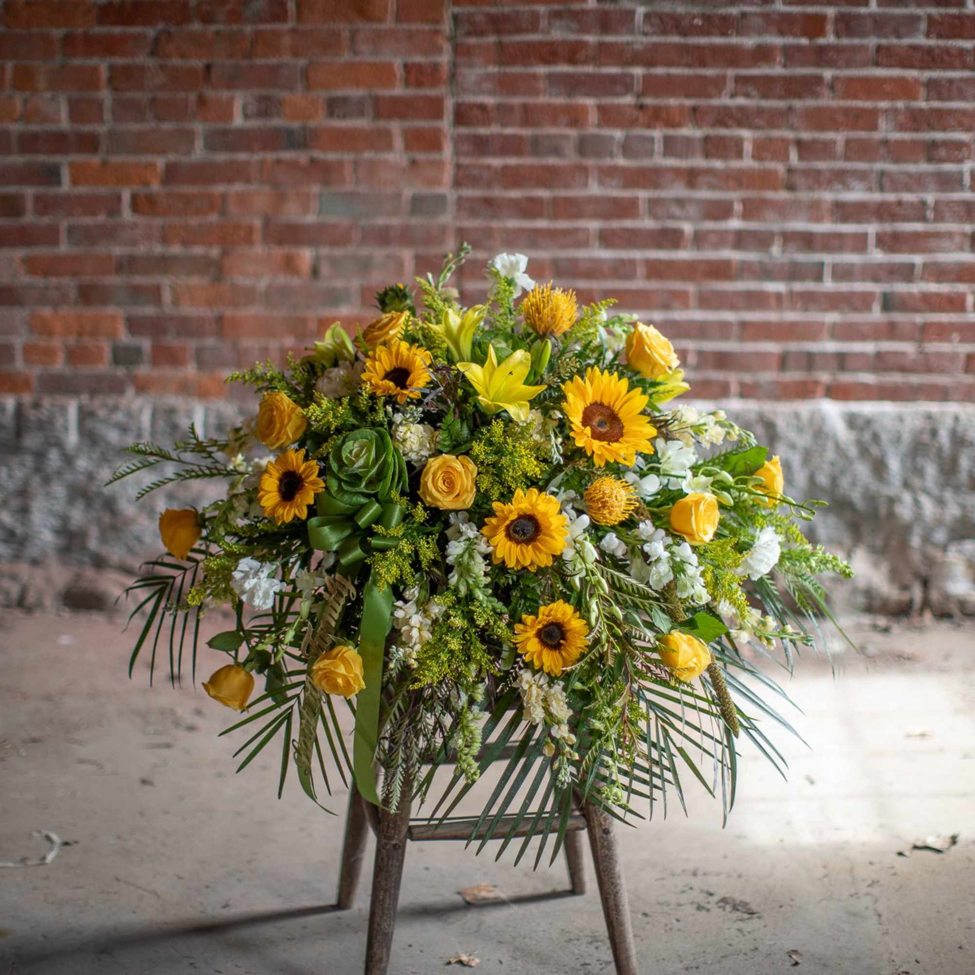 Yellow floral arrangement on a stand with sunflowers and roses