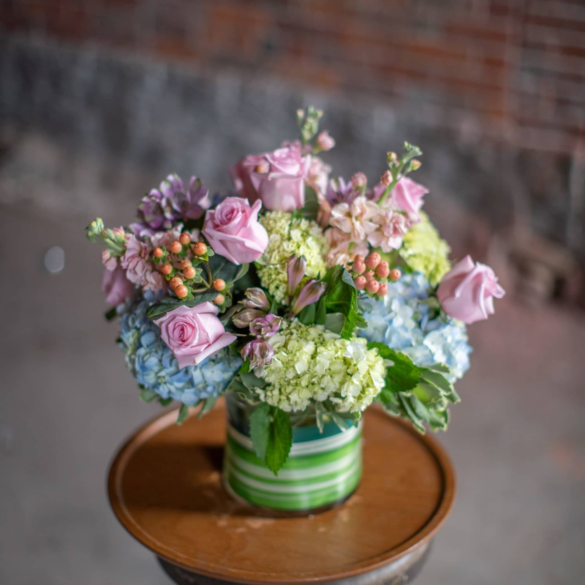 Pink roses and pastel flowers arranged in a striped vase