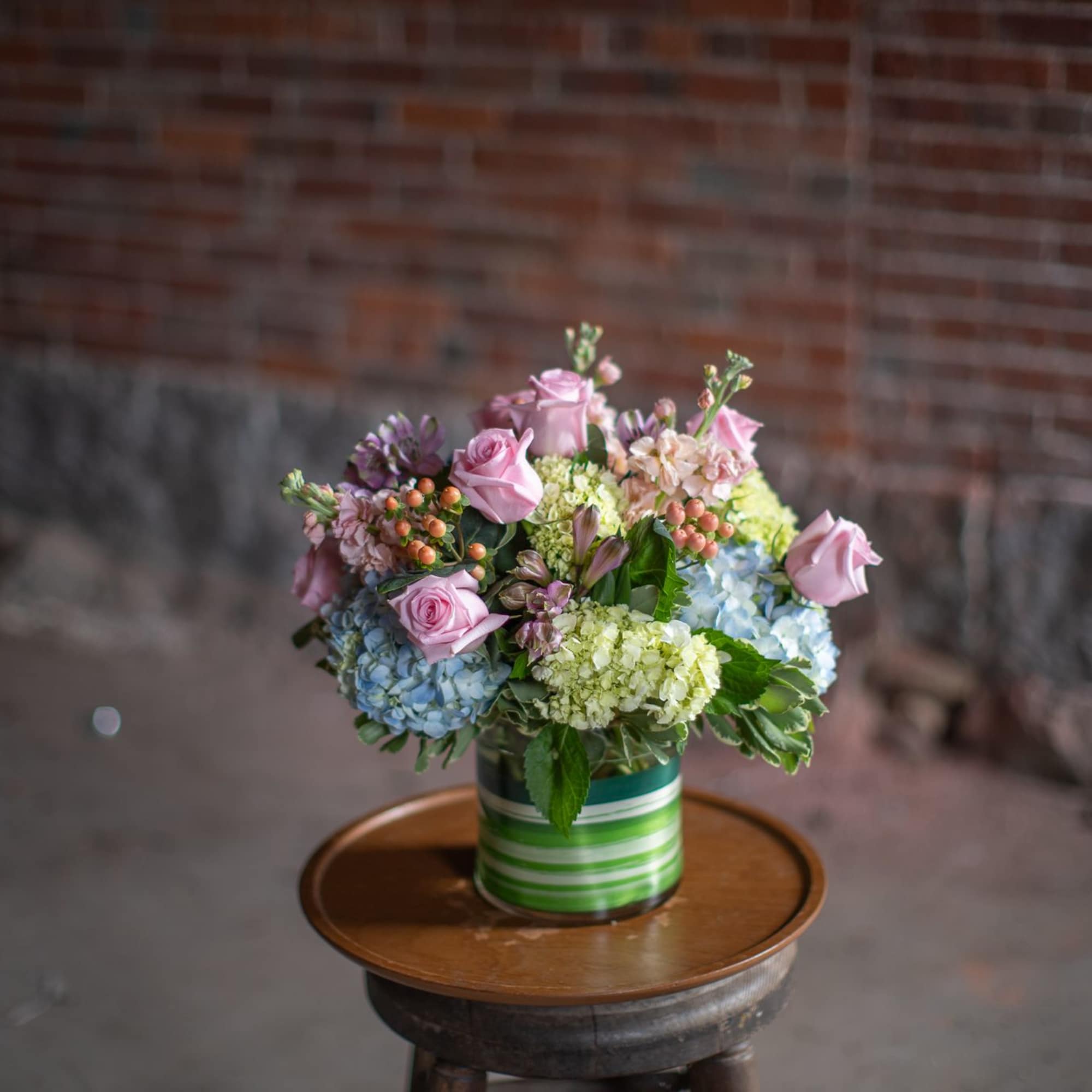 Pink roses and hydrangeas in a striped tin container