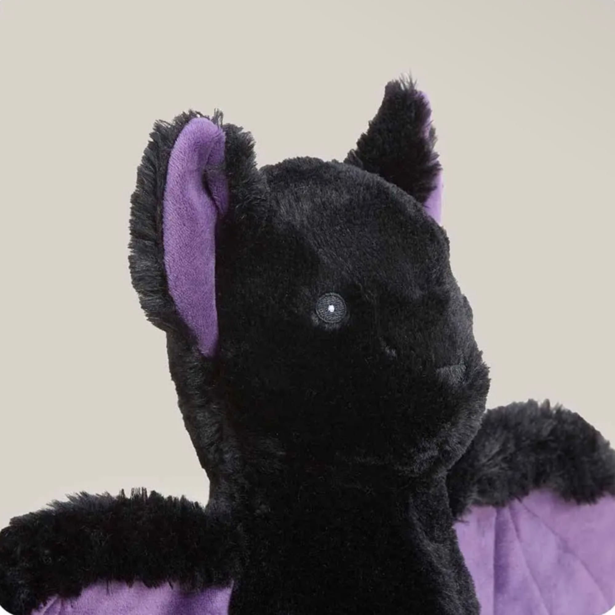 Black and purple plush bat toy on a plain background
