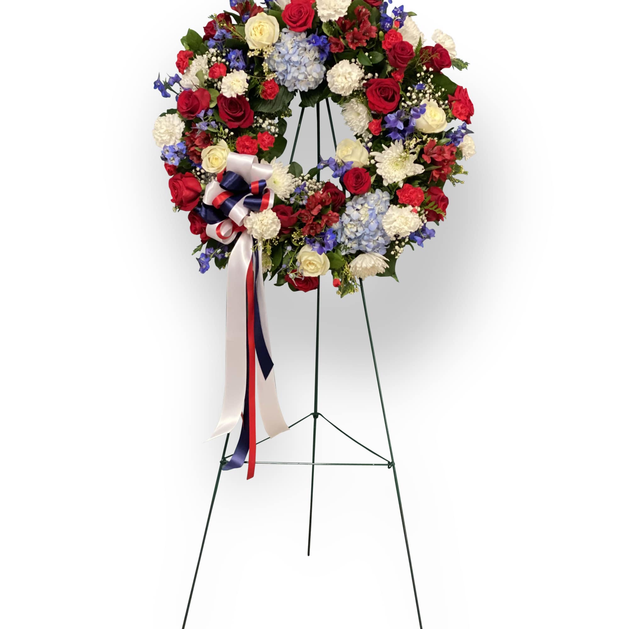 Circular standing wreath of red, white, and blue flowers on an easel