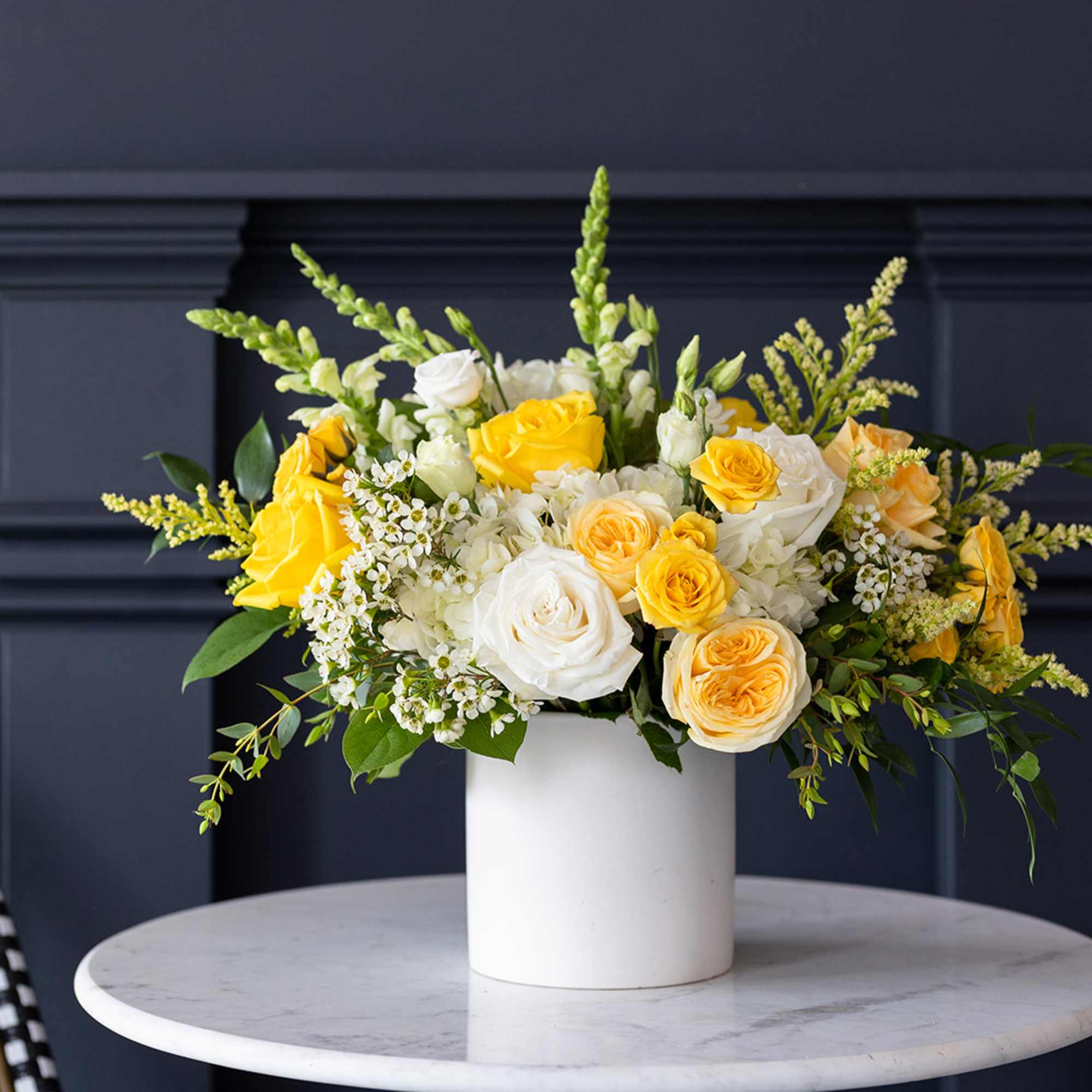 Yellow and white roses arranged in a white vase