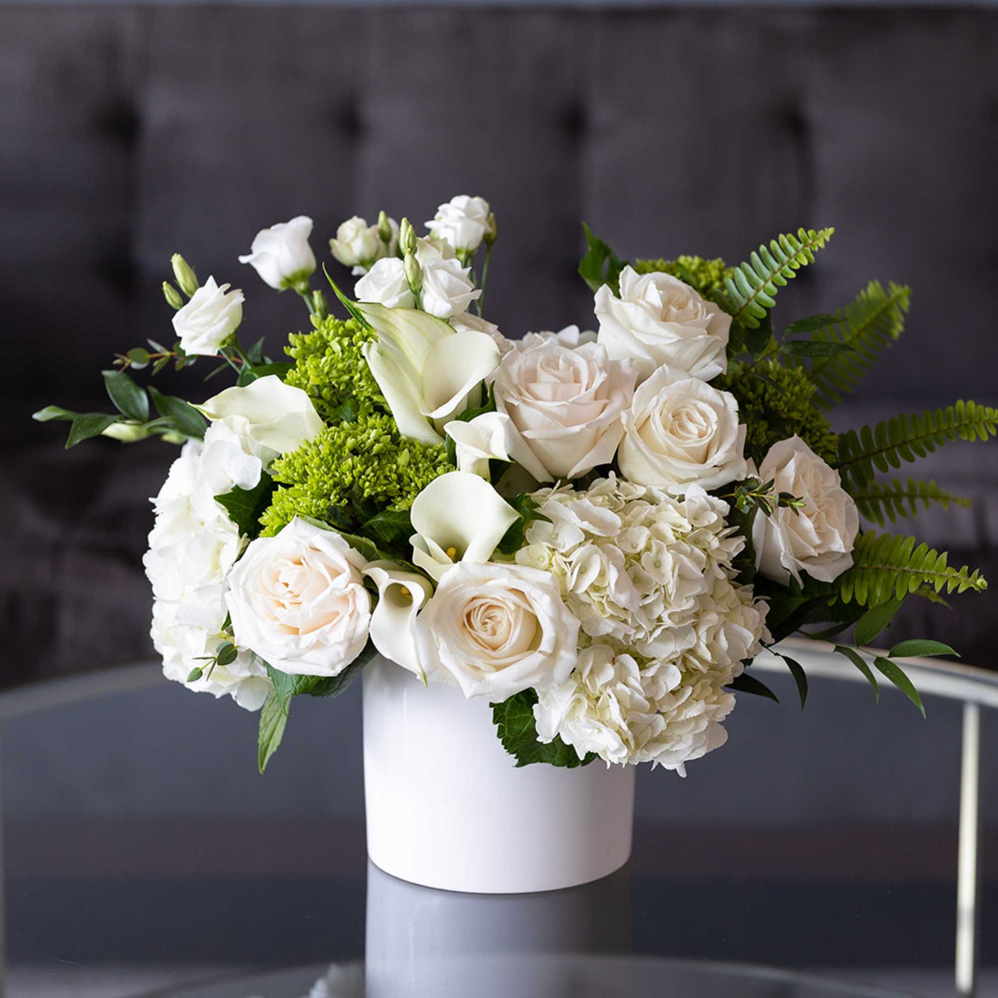 White roses and calla lilies in a white vase